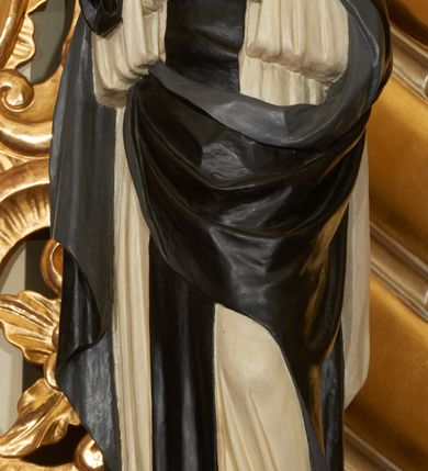 Zdjęcie nr 7: Ołtarz przyścienny, architektoniczny, jednoosiowy, jednokondygnacyjny ze zwieńczeniem. Mensa prostopadłościenna, w antepedium prostokątna, złocona rama. Prostokątna predella flankowana przed dwa wysunięte cokoły, na których ustawione są pilastry, wspierające przerwane belkowanie, zamknięte wydatnym, profilowanym gzymsem. Przed podporami ustawione są dwie figury świętych: po lewej stronie św. Teresy, a po prawej św. Kunegundy. W polu środkowym wnęka w kształcie stojącego prostokąta, zamkniętego łukiem nadwieszonym, w której umieszczona jest figura św. Antoniego Padewskiego na tle mniejszej płyciny o analogicznym kształcie. Imposty w partii fryzu ustawione są pod kątem, zdobione podwieszonymi od spodu szyszkami. Zwieńczenie w kształcie stojącego prostokąta, ujęte parą pilastrów, wspierających wyłamane belkowanie, zamknięte nad polem środkowym łukiem nadwieszonym. W polu obraz „Wniebowzięcie Najświętszej Marii Panny” w kształcie stojącego prostokąta od dołu i od góry zamkniętego łukiem nadwieszonym. Na szczycie zwieńczenia promienista gloria z monogramem maryjnym na tle obłoków. Podpory ustawione są na niskich bazach o trzonach dekorowanych płaską, skośnie oplatającą je szeroką wstęgą i o kapitelach korynckich. Boki nastawy i zwieńczenia zdobią uszaki formowane z ażurowej dekoracji rocaille’owej. Całość struktury ołtarza pokryta marmoryzacją zielono-niebieską; na cokole, fryzie, we wnęce i w zwieńczeniu cześciowo w kolorze jasnozielonym z jasnobrązowo-białym żyłkowaniem. Detale oraz profilowania pozłacane i posrebrzane. 
