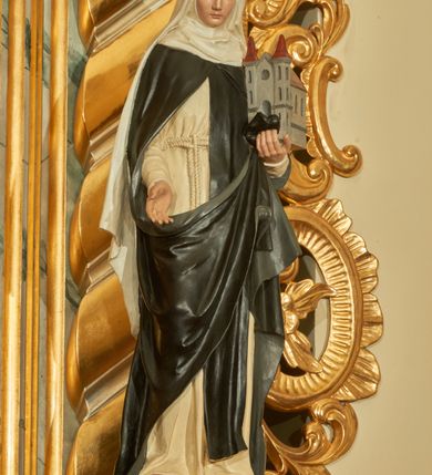 Zdjęcie nr 1: Rzeźba wolnostojąca z przedstawieniem św. Kunegundy, ustawiona na cokole. Święta została ukazana w pozycji stojącej, w delikatnym kontrapoście z prawą nogą ugiętą w kolanie. Zakonnica w lewej ręce trzyma model kościoła, a prawą opuszczoną w dół wyciąga przed siebie. Twarz owalna z długim i szerokim nosem, drobnymi ustami i dużymi oczami. Ubrana jest w biały habit, czarny szkaplerz, biały welon i podwikę oraz czarny płaszcz z prawą połą zarzuconą na lewe przedramię. Szaty drapowane są przeważnie w głębokie pionowe fałdy. Cokół prostopadłościenny o ściętych narożach, marmoryzowany, na ściance przedniej wyryty napis: „S(ANCTA) KUNEGUNDA”.