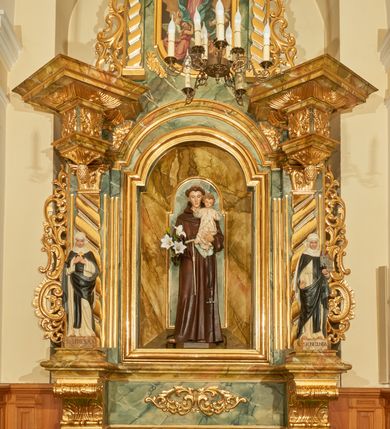 Zdjęcie nr 4: Rzeźba wolnostojąca z przedstawieniem św. Kunegundy, ustawiona na cokole. Święta została ukazana w pozycji stojącej, w delikatnym kontrapoście z prawą nogą ugiętą w kolanie. Zakonnica w lewej ręce trzyma model kościoła, a prawą opuszczoną w dół wyciąga przed siebie. Twarz owalna z długim i szerokim nosem, drobnymi ustami i dużymi oczami. Ubrana jest w biały habit, czarny szkaplerz, biały welon i podwikę oraz czarny płaszcz z prawą połą zarzuconą na lewe przedramię. Szaty drapowane są przeważnie w głębokie pionowe fałdy. Cokół prostopadłościenny o ściętych narożach, marmoryzowany, na ściance przedniej wyryty napis: „S(ANCTA) KUNEGUNDA”.