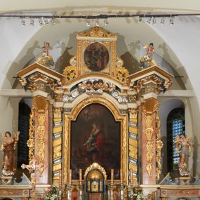 Zdjęcie nr 1: Nastawa ołtarzowa architektoniczna, jednoosiowa z bramkami, jednokondygnacyjna ze zwieńczeniem; na podwójnym cokole, zryzalitowanym w narożach. Ołtarz murowany, prostopadłościenny, w drewnianej obudowie; mensa drewniana. Antepedium proste, w formie leżącego prostokąta, obwiedzione profilowaną, złoconą ramą, w polu marmoryzowane. Tabernakulum w formie prostopadłościennej skrzynki o ściętych narożach z przodu, obite fakturowaną blachą zdobioną literami alfa i omega; w trójosiowej, drewnianej obudowie. Nad tabernakulum tron wystawienia w formie obrotowej niszy, z jednej strony zakończonej u góry wieńcem utworzonym z kwiatów i muszli, ujętej ramą utworzoną z wieńca laurowego, z glorią promienistą w polu i medalionem z napisem: „ŚWIĘTY, ŚWIETY, ŚWIĘTY”. Z drugiej strony przypominającą kaplicę kopułową z niszą z krucyfiksem, ujętą przez pilastry zdobione kampanulami; kopuła z płaskorzeźbionym przedstawieniem krzewu winnego grona i pęków zbóż. Osie boczne w formie aediculi flankowanych przez parę kolumienek, ustawionych na cokołach, dźwigających belkowanie. W prawej osi ustawiona niewielka figurka Matki Boskiej z Dzieciątkiem. Struktura ujęta uszami utworzonymi z liści akantu. 

Retabulum flankowane parą zdwojonych półfilarów, dźwigających pełne belkowanie z silnie wysuniętym gzymsem, nad polem głównym wyłamujące się w formę łuku odcinkowego oraz przerwany wolutowy przyczółek. Na osi podpór ustawione są pod kątem imposty, podtrzymywane przez płaskie muszle. W polu głównym kondygnacji obraz z przedstawieniem św. Katarzyny Aleksandryjskiej w prostokątnej, profilowanej ramie zamknięty łukiem półkolistym nadwieszonym, flankowany parą pilastrów o kapitelach kompozytowych i skręconych oraz spłaszczonych trzonach. Obraz ten stanowi zasuwę dla grupy Ukrzyżowania. Na kolejnych zasuwach obrazy: Najświętszego Serca Pana Jezusa w widzeniu św. Małgorzaty Marii Alacoque oraz papieża Jana Pawła II.
Cokoły dekorowane są płycinami z liśćmi akantu. Kondygnacja ujęta jest uszami utworzonymi z liści akantu i stylizowanej muszli. Trzony filarów zdobione są stylizowanymi kampanulami, a fryz dekorowany płycinami utworzonymi z liści akantu. Nad polem głównym zawieszone są cztery uskrzydlone główki anielskie pośród obłoków.

Zwieńczenie w formie stojącego prostokąta, ujęte parą lizen, zamknięte gzymsem i szczytem z krzyżem. W polu obraz w formie owalu z przedstawieniem św. Jakuba z Matką Boską z Pilar. Pole zwieńczenia ujęte jest spływami utworzonymi z liści akantu, wstęgi i rozetek kwiatowych; lizeny dekorowane kampanulami; w narożach pola dekoracja roślinna. Szczyt utworzony z krzyża ujętego spływami wolutowymi o wstędze przechodzącej w akant z dwiema rozetami kwiatowymi. Na przerwanym przyczółku siedzi para aniołków. Po bokach ołtarza bramki ujęte parami pilastrów na cokołach, podtrzymującymi belkowanie oraz przerwany przyczółek z cokołem pośrodku z figurami aniołów. Drzwi bramek w formie stojącego prostokąta zamkniętego łukiem półkolistym z płyciną zamkniętą łukiem półkolistym nadwieszonym w polu.
Struktura marmoryzowana w kolorze niebieskim, filary bladoróżowym; profile i ornamentyka złocone i srebrzone.
