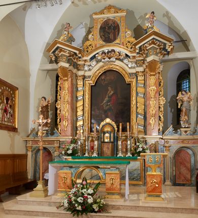 Zdjęcie nr 2: Nastawa ołtarzowa architektoniczna, jednoosiowa z bramkami, jednokondygnacyjna ze zwieńczeniem; na podwójnym cokole, zryzalitowanym w narożach. Ołtarz murowany, prostopadłościenny, w drewnianej obudowie; mensa drewniana. Antepedium proste, w formie leżącego prostokąta, obwiedzione profilowaną, złoconą ramą, w polu marmoryzowane. Tabernakulum w formie prostopadłościennej skrzynki o ściętych narożach z przodu, obite fakturowaną blachą zdobioną literami alfa i omega; w trójosiowej, drewnianej obudowie. Nad tabernakulum tron wystawienia w formie obrotowej niszy, z jednej strony zakończonej u góry wieńcem utworzonym z kwiatów i muszli, ujętej ramą utworzoną z wieńca laurowego, z glorią promienistą w polu i medalionem z napisem: „ŚWIĘTY, ŚWIETY, ŚWIĘTY”. Z drugiej strony przypominającą kaplicę kopułową z niszą z krucyfiksem, ujętą przez pilastry zdobione kampanulami; kopuła z płaskorzeźbionym przedstawieniem krzewu winnego grona i pęków zbóż. Osie boczne w formie aediculi flankowanych przez parę kolumienek, ustawionych na cokołach, dźwigających belkowanie. W prawej osi ustawiona niewielka figurka Matki Boskiej z Dzieciątkiem. Struktura ujęta uszami utworzonymi z liści akantu. 

Retabulum flankowane parą zdwojonych półfilarów, dźwigających pełne belkowanie z silnie wysuniętym gzymsem, nad polem głównym wyłamujące się w formę łuku odcinkowego oraz przerwany wolutowy przyczółek. Na osi podpór ustawione są pod kątem imposty, podtrzymywane przez płaskie muszle. W polu głównym kondygnacji obraz z przedstawieniem św. Katarzyny Aleksandryjskiej w prostokątnej, profilowanej ramie zamknięty łukiem półkolistym nadwieszonym, flankowany parą pilastrów o kapitelach kompozytowych i skręconych oraz spłaszczonych trzonach. Obraz ten stanowi zasuwę dla grupy Ukrzyżowania. Na kolejnych zasuwach obrazy: Najświętszego Serca Pana Jezusa w widzeniu św. Małgorzaty Marii Alacoque oraz papieża Jana Pawła II.
Cokoły dekorowane są płycinami z liśćmi akantu. Kondygnacja ujęta jest uszami utworzonymi z liści akantu i stylizowanej muszli. Trzony filarów zdobione są stylizowanymi kampanulami, a fryz dekorowany płycinami utworzonymi z liści akantu. Nad polem głównym zawieszone są cztery uskrzydlone główki anielskie pośród obłoków.

Zwieńczenie w formie stojącego prostokąta, ujęte parą lizen, zamknięte gzymsem i szczytem z krzyżem. W polu obraz w formie owalu z przedstawieniem św. Jakuba z Matką Boską z Pilar. Pole zwieńczenia ujęte jest spływami utworzonymi z liści akantu, wstęgi i rozetek kwiatowych; lizeny dekorowane kampanulami; w narożach pola dekoracja roślinna. Szczyt utworzony z krzyża ujętego spływami wolutowymi o wstędze przechodzącej w akant z dwiema rozetami kwiatowymi. Na przerwanym przyczółku siedzi para aniołków. Po bokach ołtarza bramki ujęte parami pilastrów na cokołach, podtrzymującymi belkowanie oraz przerwany przyczółek z cokołem pośrodku z figurami aniołów. Drzwi bramek w formie stojącego prostokąta zamkniętego łukiem półkolistym z płyciną zamkniętą łukiem półkolistym nadwieszonym w polu.
Struktura marmoryzowana w kolorze niebieskim, filary bladoróżowym; profile i ornamentyka złocone i srebrzone.
