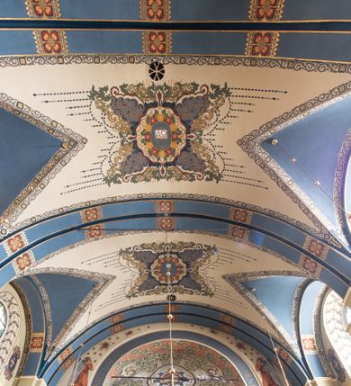 Zdjęcie nr 1: Dekoracja sklepienia nawy składa się z prostych symboli: kielicha z hostią, otwartej księgi z literami „A” i „Ω”, imienia MARIA i kotwicy. Zostały one wkomponowane w owalne medaliony w barwnej oprawie utworzonej z wieńców z żółtych i czerwonych kwiatów, złotych i zielonych wici akantów, ułożonych krzyżowo spiralnych, niebieskich ślimacznic i otaczających je stylizowanych zielonych liści akantu, między którymi przebijają się złote promienie. Owe fantazyjne kompozycje w nawie ukazane są na jasnym, kremowym tle wysklepek i niebieskich lunet i gurtów. Elementy konstrukcyjne szwów sklepiennych są podkreślone pasami z wici roślinnej. Sklepienie prezbiterium odróżnia się jaśniejszą kolorystyką. Elementy konstrukcyjne łuków podkreślają bujne czerwono-zielone kwiaty, wśród których rozpoznano piwonie. Taka sama bordiura zdobi ścianę za ołtarzem. Pośrodku umieszczono Baranka na zamkniętej księdze z chorągwią zmartwychwstania, na tle krzyża greckiego w glorii promienistej. Szwy sklepienne zaakcentowano kwiatami w układzie kandelabrowym, a wysklepki zielono-złotymi symetrycznie układającymi się wiciami roślinnymi. Na parapecie chóru muzycznego malarz przedstawił dwie sceny: „Stygmatyzacja św. Franciszka” i „Anioł grający na skrzypcach płaczącemu św. Franciszkowi”. 
