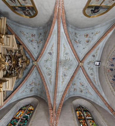 Zdjęcie nr 71: Kościół murowany z cegły, z użyciem zendrówki, na wysokim podmurowaniu z kamienia łupanego, jednonawowy, orientowany. 
Prezbiterium i nawa na planie prostokątów, nawa szersza i dłuższa od prezbiterium. Zakrystia na rzucie wydłużonego prostokąta przylega do wschodniej ściany prezbiterium, występując poza mury nawy. Prezbiterium od wschodu ujęte w narożach dwiema ukośnymi szkarpami, od południa jedną prostopadłą. Przy południowej ścianie nawy kruchta na planie kwadratu. Nawa w narożach ujęta szkarpami, od wschodu dwiema prostopadłymi, od zachodu ukośnymi. 
Prezbiterium dwuprzęsłowe, nakryte sklepieniem krzyżowo-żebrowym. Na zwornikach dwie tarcze z herbami Trzy Korony i Wieniawa. Zakrystia sklepiona kolebkowo. Nawa nakryta drewnianym stropem z kasetonami i rozetami. Kruchta sklepiona krzyżowo-żebrowo ze zwornikiem z tarczą z herbem Wieniawa. Otwór tęczowy w formie stojącego prostokąta zamkniętego łukiem ostrym. W zachodniej części nawy drewniany parapet chóru muzycznego wsparty na dwóch filarach. 
Fasada w jednej trzeciej wysokości odcięta kamiennym gzymsem kapnikowym, zakończona jodełkowym fryzem w partii muru, zwieńczona trójkątnym szczytem. Mur dekorowany zendrówką ułożoną „w zęby”, w partii szczytu w układzie rombowym. Na osi kamienny ostrołukowy portal o schodkowym nadprożu, dekorowanym krzyżującym się laskowaniem; węgary gładkie w jednej trzeciej wysokości przechodzące w piramidki i profilowanie powyżej. Nad portalem kamienna kwadratowa tablica, ujęta kamiennym obramieniem z tarczą z herbem Wieniawa. Ponad nią, na osi okulus w kamiennym obramieniu. 
Elewacje północna i południowa w części nawy w jednej trzeciej wysokości przedzielone kamiennym gzymsem kapnikowym, na zakończeniu ścian z gzymsem wieńczącym. Mur dekorowany zendrówką w układzie rombowym. Na elewacji południowej cztery okna w formie wydłużonego, stojącego prostokąta zamkniętego łukiem ostrym, w kamiennych obramieniach, podzielone laskowaniem. Południowa ściana prezbiterium zakończona gzymsem wieńczącym, w górnej części muru dekorowana zendrówką ułożoną „w zęby”. 
Szkarpy opinające nawę uskokowe, zwężające się ku górze, nakryte daszkami pulpitowymi. Szkarpy opinające prezbiterium nakryte daszkami pulpitowymi, podzielone gzymsami kapnikowymi. 
Kruchta od strony wschodniej i zachodniej podzielona kamiennym gzymsem kapnikowym, od południa zakończona gzymsem wieńczącym. Na ścianie południowej kruchty kamienny, ostrołukowy portal, o schodkowym nadprożu, dekorowanym krzyżującym się laskowaniem; węgary gładkie, w jednej trzeciej wysokości przechodzące w piramidki i profilowanie powyżej. Nad portalem kamienna tarcza z herbem Wieniawa. 
Elewacja wschodnia zwieńczona trójkątnym szczytem, w którego partii mur dekorowany jest zendrówką w układzie rombowym. Na osi okno w formie wydłużonego, stojącego prostokąta zamkniętego łukiem ostrym, w kamiennym obramieniu, zamurowane w trzech piątych wysokości, zakończone daszkiem pulpitowym. W dolnej części okna znajduje się ogrójec. 
Nawa i prezbiterium nakryte osobnymi blaszanymi dachami dwuspadowymi, kruchta i zakrystia pulpitowymi. Nad nawą blaszana wieżyczka na sygnaturkę z latarnią i hełmem baniastym.





