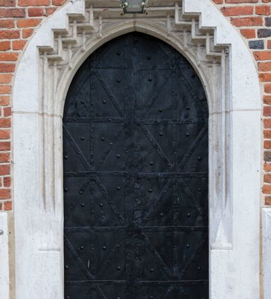 Zdjęcie nr 64: Kościół murowany z cegły, z użyciem zendrówki, na wysokim podmurowaniu z kamienia łupanego, jednonawowy, orientowany. 
Prezbiterium i nawa na planie prostokątów, nawa szersza i dłuższa od prezbiterium. Zakrystia na rzucie wydłużonego prostokąta przylega do wschodniej ściany prezbiterium, występując poza mury nawy. Prezbiterium od wschodu ujęte w narożach dwiema ukośnymi szkarpami, od południa jedną prostopadłą. Przy południowej ścianie nawy kruchta na planie kwadratu. Nawa w narożach ujęta szkarpami, od wschodu dwiema prostopadłymi, od zachodu ukośnymi. 
Prezbiterium dwuprzęsłowe, nakryte sklepieniem krzyżowo-żebrowym. Na zwornikach dwie tarcze z herbami Trzy Korony i Wieniawa. Zakrystia sklepiona kolebkowo. Nawa nakryta drewnianym stropem z kasetonami i rozetami. Kruchta sklepiona krzyżowo-żebrowo ze zwornikiem z tarczą z herbem Wieniawa. Otwór tęczowy w formie stojącego prostokąta zamkniętego łukiem ostrym. W zachodniej części nawy drewniany parapet chóru muzycznego wsparty na dwóch filarach. 
Fasada w jednej trzeciej wysokości odcięta kamiennym gzymsem kapnikowym, zakończona jodełkowym fryzem w partii muru, zwieńczona trójkątnym szczytem. Mur dekorowany zendrówką ułożoną „w zęby”, w partii szczytu w układzie rombowym. Na osi kamienny ostrołukowy portal o schodkowym nadprożu, dekorowanym krzyżującym się laskowaniem; węgary gładkie w jednej trzeciej wysokości przechodzące w piramidki i profilowanie powyżej. Nad portalem kamienna kwadratowa tablica, ujęta kamiennym obramieniem z tarczą z herbem Wieniawa. Ponad nią, na osi okulus w kamiennym obramieniu. 
Elewacje północna i południowa w części nawy w jednej trzeciej wysokości przedzielone kamiennym gzymsem kapnikowym, na zakończeniu ścian z gzymsem wieńczącym. Mur dekorowany zendrówką w układzie rombowym. Na elewacji południowej cztery okna w formie wydłużonego, stojącego prostokąta zamkniętego łukiem ostrym, w kamiennych obramieniach, podzielone laskowaniem. Południowa ściana prezbiterium zakończona gzymsem wieńczącym, w górnej części muru dekorowana zendrówką ułożoną „w zęby”. 
Szkarpy opinające nawę uskokowe, zwężające się ku górze, nakryte daszkami pulpitowymi. Szkarpy opinające prezbiterium nakryte daszkami pulpitowymi, podzielone gzymsami kapnikowymi. 
Kruchta od strony wschodniej i zachodniej podzielona kamiennym gzymsem kapnikowym, od południa zakończona gzymsem wieńczącym. Na ścianie południowej kruchty kamienny, ostrołukowy portal, o schodkowym nadprożu, dekorowanym krzyżującym się laskowaniem; węgary gładkie, w jednej trzeciej wysokości przechodzące w piramidki i profilowanie powyżej. Nad portalem kamienna tarcza z herbem Wieniawa. 
Elewacja wschodnia zwieńczona trójkątnym szczytem, w którego partii mur dekorowany jest zendrówką w układzie rombowym. Na osi okno w formie wydłużonego, stojącego prostokąta zamkniętego łukiem ostrym, w kamiennym obramieniu, zamurowane w trzech piątych wysokości, zakończone daszkiem pulpitowym. W dolnej części okna znajduje się ogrójec. 
Nawa i prezbiterium nakryte osobnymi blaszanymi dachami dwuspadowymi, kruchta i zakrystia pulpitowymi. Nad nawą blaszana wieżyczka na sygnaturkę z latarnią i hełmem baniastym.





