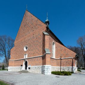 Zdjęcie nr 1: Kościół murowany z cegły, z użyciem zendrówki, na wysokim podmurowaniu z kamienia łupanego, jednonawowy, orientowany. 
Prezbiterium i nawa na planie prostokątów, nawa szersza i dłuższa od prezbiterium. Zakrystia na rzucie wydłużonego prostokąta przylega do wschodniej ściany prezbiterium, występując poza mury nawy. Prezbiterium od wschodu ujęte w narożach dwiema ukośnymi szkarpami, od południa jedną prostopadłą. Przy południowej ścianie nawy kruchta na planie kwadratu. Nawa w narożach ujęta szkarpami, od wschodu dwiema prostopadłymi, od zachodu ukośnymi. 
Prezbiterium dwuprzęsłowe, nakryte sklepieniem krzyżowo-żebrowym. Na zwornikach dwie tarcze z herbami Trzy Korony i Wieniawa. Zakrystia sklepiona kolebkowo. Nawa nakryta drewnianym stropem z kasetonami i rozetami. Kruchta sklepiona krzyżowo-żebrowo ze zwornikiem z tarczą z herbem Wieniawa. Otwór tęczowy w formie stojącego prostokąta zamkniętego łukiem ostrym. W zachodniej części nawy drewniany parapet chóru muzycznego wsparty na dwóch filarach. 
Fasada w jednej trzeciej wysokości odcięta kamiennym gzymsem kapnikowym, zakończona jodełkowym fryzem w partii muru, zwieńczona trójkątnym szczytem. Mur dekorowany zendrówką ułożoną „w zęby”, w partii szczytu w układzie rombowym. Na osi kamienny ostrołukowy portal o schodkowym nadprożu, dekorowanym krzyżującym się laskowaniem; węgary gładkie w jednej trzeciej wysokości przechodzące w piramidki i profilowanie powyżej. Nad portalem kamienna kwadratowa tablica, ujęta kamiennym obramieniem z tarczą z herbem Wieniawa. Ponad nią, na osi okulus w kamiennym obramieniu. 
Elewacje północna i południowa w części nawy w jednej trzeciej wysokości przedzielone kamiennym gzymsem kapnikowym, na zakończeniu ścian z gzymsem wieńczącym. Mur dekorowany zendrówką w układzie rombowym. Na elewacji południowej cztery okna w formie wydłużonego, stojącego prostokąta zamkniętego łukiem ostrym, w kamiennych obramieniach, podzielone laskowaniem. Południowa ściana prezbiterium zakończona gzymsem wieńczącym, w górnej części muru dekorowana zendrówką ułożoną „w zęby”. 
Szkarpy opinające nawę uskokowe, zwężające się ku górze, nakryte daszkami pulpitowymi. Szkarpy opinające prezbiterium nakryte daszkami pulpitowymi, podzielone gzymsami kapnikowymi. 
Kruchta od strony wschodniej i zachodniej podzielona kamiennym gzymsem kapnikowym, od południa zakończona gzymsem wieńczącym. Na ścianie południowej kruchty kamienny, ostrołukowy portal, o schodkowym nadprożu, dekorowanym krzyżującym się laskowaniem; węgary gładkie, w jednej trzeciej wysokości przechodzące w piramidki i profilowanie powyżej. Nad portalem kamienna tarcza z herbem Wieniawa. 
Elewacja wschodnia zwieńczona trójkątnym szczytem, w którego partii mur dekorowany jest zendrówką w układzie rombowym. Na osi okno w formie wydłużonego, stojącego prostokąta zamkniętego łukiem ostrym, w kamiennym obramieniu, zamurowane w trzech piątych wysokości, zakończone daszkiem pulpitowym. W dolnej części okna znajduje się ogrójec. 
Nawa i prezbiterium nakryte osobnymi blaszanymi dachami dwuspadowymi, kruchta i zakrystia pulpitowymi. Nad nawą blaszana wieżyczka na sygnaturkę z latarnią i hełmem baniastym.





