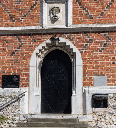 Zdjęcie nr 54: Kościół murowany z cegły, z użyciem zendrówki, na wysokim podmurowaniu z kamienia łupanego, jednonawowy, orientowany. 
Prezbiterium i nawa na planie prostokątów, nawa szersza i dłuższa od prezbiterium. Zakrystia na rzucie wydłużonego prostokąta przylega do wschodniej ściany prezbiterium, występując poza mury nawy. Prezbiterium od wschodu ujęte w narożach dwiema ukośnymi szkarpami, od południa jedną prostopadłą. Przy południowej ścianie nawy kruchta na planie kwadratu. Nawa w narożach ujęta szkarpami, od wschodu dwiema prostopadłymi, od zachodu ukośnymi. 
Prezbiterium dwuprzęsłowe, nakryte sklepieniem krzyżowo-żebrowym. Na zwornikach dwie tarcze z herbami Trzy Korony i Wieniawa. Zakrystia sklepiona kolebkowo. Nawa nakryta drewnianym stropem z kasetonami i rozetami. Kruchta sklepiona krzyżowo-żebrowo ze zwornikiem z tarczą z herbem Wieniawa. Otwór tęczowy w formie stojącego prostokąta zamkniętego łukiem ostrym. W zachodniej części nawy drewniany parapet chóru muzycznego wsparty na dwóch filarach. 
Fasada w jednej trzeciej wysokości odcięta kamiennym gzymsem kapnikowym, zakończona jodełkowym fryzem w partii muru, zwieńczona trójkątnym szczytem. Mur dekorowany zendrówką ułożoną „w zęby”, w partii szczytu w układzie rombowym. Na osi kamienny ostrołukowy portal o schodkowym nadprożu, dekorowanym krzyżującym się laskowaniem; węgary gładkie w jednej trzeciej wysokości przechodzące w piramidki i profilowanie powyżej. Nad portalem kamienna kwadratowa tablica, ujęta kamiennym obramieniem z tarczą z herbem Wieniawa. Ponad nią, na osi okulus w kamiennym obramieniu. 
Elewacje północna i południowa w części nawy w jednej trzeciej wysokości przedzielone kamiennym gzymsem kapnikowym, na zakończeniu ścian z gzymsem wieńczącym. Mur dekorowany zendrówką w układzie rombowym. Na elewacji południowej cztery okna w formie wydłużonego, stojącego prostokąta zamkniętego łukiem ostrym, w kamiennych obramieniach, podzielone laskowaniem. Południowa ściana prezbiterium zakończona gzymsem wieńczącym, w górnej części muru dekorowana zendrówką ułożoną „w zęby”. 
Szkarpy opinające nawę uskokowe, zwężające się ku górze, nakryte daszkami pulpitowymi. Szkarpy opinające prezbiterium nakryte daszkami pulpitowymi, podzielone gzymsami kapnikowymi. 
Kruchta od strony wschodniej i zachodniej podzielona kamiennym gzymsem kapnikowym, od południa zakończona gzymsem wieńczącym. Na ścianie południowej kruchty kamienny, ostrołukowy portal, o schodkowym nadprożu, dekorowanym krzyżującym się laskowaniem; węgary gładkie, w jednej trzeciej wysokości przechodzące w piramidki i profilowanie powyżej. Nad portalem kamienna tarcza z herbem Wieniawa. 
Elewacja wschodnia zwieńczona trójkątnym szczytem, w którego partii mur dekorowany jest zendrówką w układzie rombowym. Na osi okno w formie wydłużonego, stojącego prostokąta zamkniętego łukiem ostrym, w kamiennym obramieniu, zamurowane w trzech piątych wysokości, zakończone daszkiem pulpitowym. W dolnej części okna znajduje się ogrójec. 
Nawa i prezbiterium nakryte osobnymi blaszanymi dachami dwuspadowymi, kruchta i zakrystia pulpitowymi. Nad nawą blaszana wieżyczka na sygnaturkę z latarnią i hełmem baniastym.





