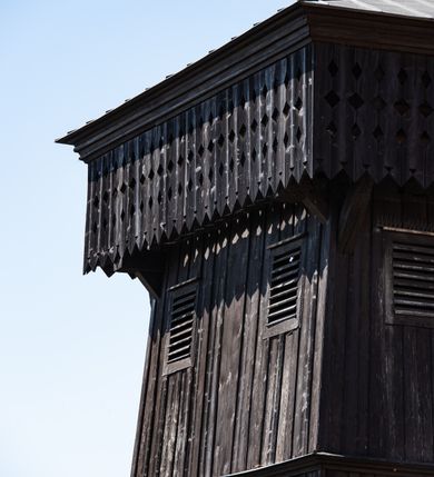 Zdjęcie nr 51: Kościół murowany z cegły, z użyciem zendrówki, na wysokim podmurowaniu z kamienia łupanego, jednonawowy, orientowany. 
Prezbiterium i nawa na planie prostokątów, nawa szersza i dłuższa od prezbiterium. Zakrystia na rzucie wydłużonego prostokąta przylega do wschodniej ściany prezbiterium, występując poza mury nawy. Prezbiterium od wschodu ujęte w narożach dwiema ukośnymi szkarpami, od południa jedną prostopadłą. Przy południowej ścianie nawy kruchta na planie kwadratu. Nawa w narożach ujęta szkarpami, od wschodu dwiema prostopadłymi, od zachodu ukośnymi. 
Prezbiterium dwuprzęsłowe, nakryte sklepieniem krzyżowo-żebrowym. Na zwornikach dwie tarcze z herbami Trzy Korony i Wieniawa. Zakrystia sklepiona kolebkowo. Nawa nakryta drewnianym stropem z kasetonami i rozetami. Kruchta sklepiona krzyżowo-żebrowo ze zwornikiem z tarczą z herbem Wieniawa. Otwór tęczowy w formie stojącego prostokąta zamkniętego łukiem ostrym. W zachodniej części nawy drewniany parapet chóru muzycznego wsparty na dwóch filarach. 
Fasada w jednej trzeciej wysokości odcięta kamiennym gzymsem kapnikowym, zakończona jodełkowym fryzem w partii muru, zwieńczona trójkątnym szczytem. Mur dekorowany zendrówką ułożoną „w zęby”, w partii szczytu w układzie rombowym. Na osi kamienny ostrołukowy portal o schodkowym nadprożu, dekorowanym krzyżującym się laskowaniem; węgary gładkie w jednej trzeciej wysokości przechodzące w piramidki i profilowanie powyżej. Nad portalem kamienna kwadratowa tablica, ujęta kamiennym obramieniem z tarczą z herbem Wieniawa. Ponad nią, na osi okulus w kamiennym obramieniu. 
Elewacje północna i południowa w części nawy w jednej trzeciej wysokości przedzielone kamiennym gzymsem kapnikowym, na zakończeniu ścian z gzymsem wieńczącym. Mur dekorowany zendrówką w układzie rombowym. Na elewacji południowej cztery okna w formie wydłużonego, stojącego prostokąta zamkniętego łukiem ostrym, w kamiennych obramieniach, podzielone laskowaniem. Południowa ściana prezbiterium zakończona gzymsem wieńczącym, w górnej części muru dekorowana zendrówką ułożoną „w zęby”. 
Szkarpy opinające nawę uskokowe, zwężające się ku górze, nakryte daszkami pulpitowymi. Szkarpy opinające prezbiterium nakryte daszkami pulpitowymi, podzielone gzymsami kapnikowymi. 
Kruchta od strony wschodniej i zachodniej podzielona kamiennym gzymsem kapnikowym, od południa zakończona gzymsem wieńczącym. Na ścianie południowej kruchty kamienny, ostrołukowy portal, o schodkowym nadprożu, dekorowanym krzyżującym się laskowaniem; węgary gładkie, w jednej trzeciej wysokości przechodzące w piramidki i profilowanie powyżej. Nad portalem kamienna tarcza z herbem Wieniawa. 
Elewacja wschodnia zwieńczona trójkątnym szczytem, w którego partii mur dekorowany jest zendrówką w układzie rombowym. Na osi okno w formie wydłużonego, stojącego prostokąta zamkniętego łukiem ostrym, w kamiennym obramieniu, zamurowane w trzech piątych wysokości, zakończone daszkiem pulpitowym. W dolnej części okna znajduje się ogrójec. 
Nawa i prezbiterium nakryte osobnymi blaszanymi dachami dwuspadowymi, kruchta i zakrystia pulpitowymi. Nad nawą blaszana wieżyczka na sygnaturkę z latarnią i hełmem baniastym.





