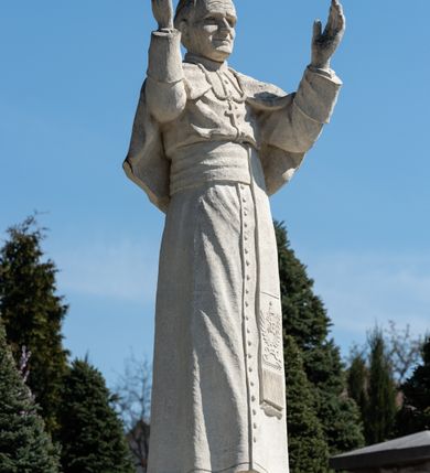 Zdjęcie nr 18: Kościół murowany z cegły, z użyciem zendrówki, na wysokim podmurowaniu z kamienia łupanego, jednonawowy, orientowany. 
Prezbiterium i nawa na planie prostokątów, nawa szersza i dłuższa od prezbiterium. Zakrystia na rzucie wydłużonego prostokąta przylega do wschodniej ściany prezbiterium, występując poza mury nawy. Prezbiterium od wschodu ujęte w narożach dwiema ukośnymi szkarpami, od południa jedną prostopadłą. Przy południowej ścianie nawy kruchta na planie kwadratu. Nawa w narożach ujęta szkarpami, od wschodu dwiema prostopadłymi, od zachodu ukośnymi. 
Prezbiterium dwuprzęsłowe, nakryte sklepieniem krzyżowo-żebrowym. Na zwornikach dwie tarcze z herbami Trzy Korony i Wieniawa. Zakrystia sklepiona kolebkowo. Nawa nakryta drewnianym stropem z kasetonami i rozetami. Kruchta sklepiona krzyżowo-żebrowo ze zwornikiem z tarczą z herbem Wieniawa. Otwór tęczowy w formie stojącego prostokąta zamkniętego łukiem ostrym. W zachodniej części nawy drewniany parapet chóru muzycznego wsparty na dwóch filarach. 
Fasada w jednej trzeciej wysokości odcięta kamiennym gzymsem kapnikowym, zakończona jodełkowym fryzem w partii muru, zwieńczona trójkątnym szczytem. Mur dekorowany zendrówką ułożoną „w zęby”, w partii szczytu w układzie rombowym. Na osi kamienny ostrołukowy portal o schodkowym nadprożu, dekorowanym krzyżującym się laskowaniem; węgary gładkie w jednej trzeciej wysokości przechodzące w piramidki i profilowanie powyżej. Nad portalem kamienna kwadratowa tablica, ujęta kamiennym obramieniem z tarczą z herbem Wieniawa. Ponad nią, na osi okulus w kamiennym obramieniu. 
Elewacje północna i południowa w części nawy w jednej trzeciej wysokości przedzielone kamiennym gzymsem kapnikowym, na zakończeniu ścian z gzymsem wieńczącym. Mur dekorowany zendrówką w układzie rombowym. Na elewacji południowej cztery okna w formie wydłużonego, stojącego prostokąta zamkniętego łukiem ostrym, w kamiennych obramieniach, podzielone laskowaniem. Południowa ściana prezbiterium zakończona gzymsem wieńczącym, w górnej części muru dekorowana zendrówką ułożoną „w zęby”. 
Szkarpy opinające nawę uskokowe, zwężające się ku górze, nakryte daszkami pulpitowymi. Szkarpy opinające prezbiterium nakryte daszkami pulpitowymi, podzielone gzymsami kapnikowymi. 
Kruchta od strony wschodniej i zachodniej podzielona kamiennym gzymsem kapnikowym, od południa zakończona gzymsem wieńczącym. Na ścianie południowej kruchty kamienny, ostrołukowy portal, o schodkowym nadprożu, dekorowanym krzyżującym się laskowaniem; węgary gładkie, w jednej trzeciej wysokości przechodzące w piramidki i profilowanie powyżej. Nad portalem kamienna tarcza z herbem Wieniawa. 
Elewacja wschodnia zwieńczona trójkątnym szczytem, w którego partii mur dekorowany jest zendrówką w układzie rombowym. Na osi okno w formie wydłużonego, stojącego prostokąta zamkniętego łukiem ostrym, w kamiennym obramieniu, zamurowane w trzech piątych wysokości, zakończone daszkiem pulpitowym. W dolnej części okna znajduje się ogrójec. 
Nawa i prezbiterium nakryte osobnymi blaszanymi dachami dwuspadowymi, kruchta i zakrystia pulpitowymi. Nad nawą blaszana wieżyczka na sygnaturkę z latarnią i hełmem baniastym.





