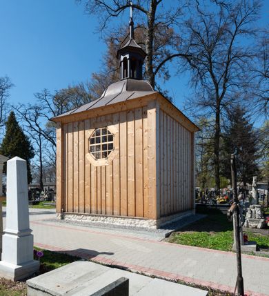 Zdjęcie nr 25: Kościół murowany z cegły, z użyciem zendrówki, na wysokim podmurowaniu z kamienia łupanego, jednonawowy, orientowany. 
Prezbiterium i nawa na planie prostokątów, nawa szersza i dłuższa od prezbiterium. Zakrystia na rzucie wydłużonego prostokąta przylega do wschodniej ściany prezbiterium, występując poza mury nawy. Prezbiterium od wschodu ujęte w narożach dwiema ukośnymi szkarpami, od południa jedną prostopadłą. Przy południowej ścianie nawy kruchta na planie kwadratu. Nawa w narożach ujęta szkarpami, od wschodu dwiema prostopadłymi, od zachodu ukośnymi. 
Prezbiterium dwuprzęsłowe, nakryte sklepieniem krzyżowo-żebrowym. Na zwornikach dwie tarcze z herbami Trzy Korony i Wieniawa. Zakrystia sklepiona kolebkowo. Nawa nakryta drewnianym stropem z kasetonami i rozetami. Kruchta sklepiona krzyżowo-żebrowo ze zwornikiem z tarczą z herbem Wieniawa. Otwór tęczowy w formie stojącego prostokąta zamkniętego łukiem ostrym. W zachodniej części nawy drewniany parapet chóru muzycznego wsparty na dwóch filarach. 
Fasada w jednej trzeciej wysokości odcięta kamiennym gzymsem kapnikowym, zakończona jodełkowym fryzem w partii muru, zwieńczona trójkątnym szczytem. Mur dekorowany zendrówką ułożoną „w zęby”, w partii szczytu w układzie rombowym. Na osi kamienny ostrołukowy portal o schodkowym nadprożu, dekorowanym krzyżującym się laskowaniem; węgary gładkie w jednej trzeciej wysokości przechodzące w piramidki i profilowanie powyżej. Nad portalem kamienna kwadratowa tablica, ujęta kamiennym obramieniem z tarczą z herbem Wieniawa. Ponad nią, na osi okulus w kamiennym obramieniu. 
Elewacje północna i południowa w części nawy w jednej trzeciej wysokości przedzielone kamiennym gzymsem kapnikowym, na zakończeniu ścian z gzymsem wieńczącym. Mur dekorowany zendrówką w układzie rombowym. Na elewacji południowej cztery okna w formie wydłużonego, stojącego prostokąta zamkniętego łukiem ostrym, w kamiennych obramieniach, podzielone laskowaniem. Południowa ściana prezbiterium zakończona gzymsem wieńczącym, w górnej części muru dekorowana zendrówką ułożoną „w zęby”. 
Szkarpy opinające nawę uskokowe, zwężające się ku górze, nakryte daszkami pulpitowymi. Szkarpy opinające prezbiterium nakryte daszkami pulpitowymi, podzielone gzymsami kapnikowymi. 
Kruchta od strony wschodniej i zachodniej podzielona kamiennym gzymsem kapnikowym, od południa zakończona gzymsem wieńczącym. Na ścianie południowej kruchty kamienny, ostrołukowy portal, o schodkowym nadprożu, dekorowanym krzyżującym się laskowaniem; węgary gładkie, w jednej trzeciej wysokości przechodzące w piramidki i profilowanie powyżej. Nad portalem kamienna tarcza z herbem Wieniawa. 
Elewacja wschodnia zwieńczona trójkątnym szczytem, w którego partii mur dekorowany jest zendrówką w układzie rombowym. Na osi okno w formie wydłużonego, stojącego prostokąta zamkniętego łukiem ostrym, w kamiennym obramieniu, zamurowane w trzech piątych wysokości, zakończone daszkiem pulpitowym. W dolnej części okna znajduje się ogrójec. 
Nawa i prezbiterium nakryte osobnymi blaszanymi dachami dwuspadowymi, kruchta i zakrystia pulpitowymi. Nad nawą blaszana wieżyczka na sygnaturkę z latarnią i hełmem baniastym.





