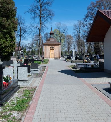 Zdjęcie nr 26: Kościół murowany z cegły, z użyciem zendrówki, na wysokim podmurowaniu z kamienia łupanego, jednonawowy, orientowany. 
Prezbiterium i nawa na planie prostokątów, nawa szersza i dłuższa od prezbiterium. Zakrystia na rzucie wydłużonego prostokąta przylega do wschodniej ściany prezbiterium, występując poza mury nawy. Prezbiterium od wschodu ujęte w narożach dwiema ukośnymi szkarpami, od południa jedną prostopadłą. Przy południowej ścianie nawy kruchta na planie kwadratu. Nawa w narożach ujęta szkarpami, od wschodu dwiema prostopadłymi, od zachodu ukośnymi. 
Prezbiterium dwuprzęsłowe, nakryte sklepieniem krzyżowo-żebrowym. Na zwornikach dwie tarcze z herbami Trzy Korony i Wieniawa. Zakrystia sklepiona kolebkowo. Nawa nakryta drewnianym stropem z kasetonami i rozetami. Kruchta sklepiona krzyżowo-żebrowo ze zwornikiem z tarczą z herbem Wieniawa. Otwór tęczowy w formie stojącego prostokąta zamkniętego łukiem ostrym. W zachodniej części nawy drewniany parapet chóru muzycznego wsparty na dwóch filarach. 
Fasada w jednej trzeciej wysokości odcięta kamiennym gzymsem kapnikowym, zakończona jodełkowym fryzem w partii muru, zwieńczona trójkątnym szczytem. Mur dekorowany zendrówką ułożoną „w zęby”, w partii szczytu w układzie rombowym. Na osi kamienny ostrołukowy portal o schodkowym nadprożu, dekorowanym krzyżującym się laskowaniem; węgary gładkie w jednej trzeciej wysokości przechodzące w piramidki i profilowanie powyżej. Nad portalem kamienna kwadratowa tablica, ujęta kamiennym obramieniem z tarczą z herbem Wieniawa. Ponad nią, na osi okulus w kamiennym obramieniu. 
Elewacje północna i południowa w części nawy w jednej trzeciej wysokości przedzielone kamiennym gzymsem kapnikowym, na zakończeniu ścian z gzymsem wieńczącym. Mur dekorowany zendrówką w układzie rombowym. Na elewacji południowej cztery okna w formie wydłużonego, stojącego prostokąta zamkniętego łukiem ostrym, w kamiennych obramieniach, podzielone laskowaniem. Południowa ściana prezbiterium zakończona gzymsem wieńczącym, w górnej części muru dekorowana zendrówką ułożoną „w zęby”. 
Szkarpy opinające nawę uskokowe, zwężające się ku górze, nakryte daszkami pulpitowymi. Szkarpy opinające prezbiterium nakryte daszkami pulpitowymi, podzielone gzymsami kapnikowymi. 
Kruchta od strony wschodniej i zachodniej podzielona kamiennym gzymsem kapnikowym, od południa zakończona gzymsem wieńczącym. Na ścianie południowej kruchty kamienny, ostrołukowy portal, o schodkowym nadprożu, dekorowanym krzyżującym się laskowaniem; węgary gładkie, w jednej trzeciej wysokości przechodzące w piramidki i profilowanie powyżej. Nad portalem kamienna tarcza z herbem Wieniawa. 
Elewacja wschodnia zwieńczona trójkątnym szczytem, w którego partii mur dekorowany jest zendrówką w układzie rombowym. Na osi okno w formie wydłużonego, stojącego prostokąta zamkniętego łukiem ostrym, w kamiennym obramieniu, zamurowane w trzech piątych wysokości, zakończone daszkiem pulpitowym. W dolnej części okna znajduje się ogrójec. 
Nawa i prezbiterium nakryte osobnymi blaszanymi dachami dwuspadowymi, kruchta i zakrystia pulpitowymi. Nad nawą blaszana wieżyczka na sygnaturkę z latarnią i hełmem baniastym.





