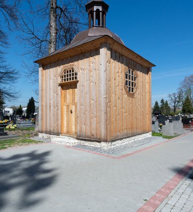 Zdjęcie nr 24: Kościół murowany z cegły, z użyciem zendrówki, na wysokim podmurowaniu z kamienia łupanego, jednonawowy, orientowany. 
Prezbiterium i nawa na planie prostokątów, nawa szersza i dłuższa od prezbiterium. Zakrystia na rzucie wydłużonego prostokąta przylega do wschodniej ściany prezbiterium, występując poza mury nawy. Prezbiterium od wschodu ujęte w narożach dwiema ukośnymi szkarpami, od południa jedną prostopadłą. Przy południowej ścianie nawy kruchta na planie kwadratu. Nawa w narożach ujęta szkarpami, od wschodu dwiema prostopadłymi, od zachodu ukośnymi. 
Prezbiterium dwuprzęsłowe, nakryte sklepieniem krzyżowo-żebrowym. Na zwornikach dwie tarcze z herbami Trzy Korony i Wieniawa. Zakrystia sklepiona kolebkowo. Nawa nakryta drewnianym stropem z kasetonami i rozetami. Kruchta sklepiona krzyżowo-żebrowo ze zwornikiem z tarczą z herbem Wieniawa. Otwór tęczowy w formie stojącego prostokąta zamkniętego łukiem ostrym. W zachodniej części nawy drewniany parapet chóru muzycznego wsparty na dwóch filarach. 
Fasada w jednej trzeciej wysokości odcięta kamiennym gzymsem kapnikowym, zakończona jodełkowym fryzem w partii muru, zwieńczona trójkątnym szczytem. Mur dekorowany zendrówką ułożoną „w zęby”, w partii szczytu w układzie rombowym. Na osi kamienny ostrołukowy portal o schodkowym nadprożu, dekorowanym krzyżującym się laskowaniem; węgary gładkie w jednej trzeciej wysokości przechodzące w piramidki i profilowanie powyżej. Nad portalem kamienna kwadratowa tablica, ujęta kamiennym obramieniem z tarczą z herbem Wieniawa. Ponad nią, na osi okulus w kamiennym obramieniu. 
Elewacje północna i południowa w części nawy w jednej trzeciej wysokości przedzielone kamiennym gzymsem kapnikowym, na zakończeniu ścian z gzymsem wieńczącym. Mur dekorowany zendrówką w układzie rombowym. Na elewacji południowej cztery okna w formie wydłużonego, stojącego prostokąta zamkniętego łukiem ostrym, w kamiennych obramieniach, podzielone laskowaniem. Południowa ściana prezbiterium zakończona gzymsem wieńczącym, w górnej części muru dekorowana zendrówką ułożoną „w zęby”. 
Szkarpy opinające nawę uskokowe, zwężające się ku górze, nakryte daszkami pulpitowymi. Szkarpy opinające prezbiterium nakryte daszkami pulpitowymi, podzielone gzymsami kapnikowymi. 
Kruchta od strony wschodniej i zachodniej podzielona kamiennym gzymsem kapnikowym, od południa zakończona gzymsem wieńczącym. Na ścianie południowej kruchty kamienny, ostrołukowy portal, o schodkowym nadprożu, dekorowanym krzyżującym się laskowaniem; węgary gładkie, w jednej trzeciej wysokości przechodzące w piramidki i profilowanie powyżej. Nad portalem kamienna tarcza z herbem Wieniawa. 
Elewacja wschodnia zwieńczona trójkątnym szczytem, w którego partii mur dekorowany jest zendrówką w układzie rombowym. Na osi okno w formie wydłużonego, stojącego prostokąta zamkniętego łukiem ostrym, w kamiennym obramieniu, zamurowane w trzech piątych wysokości, zakończone daszkiem pulpitowym. W dolnej części okna znajduje się ogrójec. 
Nawa i prezbiterium nakryte osobnymi blaszanymi dachami dwuspadowymi, kruchta i zakrystia pulpitowymi. Nad nawą blaszana wieżyczka na sygnaturkę z latarnią i hełmem baniastym.





