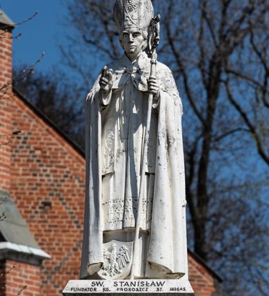 Zdjęcie nr 17: Kościół murowany z cegły, z użyciem zendrówki, na wysokim podmurowaniu z kamienia łupanego, jednonawowy, orientowany. 
Prezbiterium i nawa na planie prostokątów, nawa szersza i dłuższa od prezbiterium. Zakrystia na rzucie wydłużonego prostokąta przylega do wschodniej ściany prezbiterium, występując poza mury nawy. Prezbiterium od wschodu ujęte w narożach dwiema ukośnymi szkarpami, od południa jedną prostopadłą. Przy południowej ścianie nawy kruchta na planie kwadratu. Nawa w narożach ujęta szkarpami, od wschodu dwiema prostopadłymi, od zachodu ukośnymi. 
Prezbiterium dwuprzęsłowe, nakryte sklepieniem krzyżowo-żebrowym. Na zwornikach dwie tarcze z herbami Trzy Korony i Wieniawa. Zakrystia sklepiona kolebkowo. Nawa nakryta drewnianym stropem z kasetonami i rozetami. Kruchta sklepiona krzyżowo-żebrowo ze zwornikiem z tarczą z herbem Wieniawa. Otwór tęczowy w formie stojącego prostokąta zamkniętego łukiem ostrym. W zachodniej części nawy drewniany parapet chóru muzycznego wsparty na dwóch filarach. 
Fasada w jednej trzeciej wysokości odcięta kamiennym gzymsem kapnikowym, zakończona jodełkowym fryzem w partii muru, zwieńczona trójkątnym szczytem. Mur dekorowany zendrówką ułożoną „w zęby”, w partii szczytu w układzie rombowym. Na osi kamienny ostrołukowy portal o schodkowym nadprożu, dekorowanym krzyżującym się laskowaniem; węgary gładkie w jednej trzeciej wysokości przechodzące w piramidki i profilowanie powyżej. Nad portalem kamienna kwadratowa tablica, ujęta kamiennym obramieniem z tarczą z herbem Wieniawa. Ponad nią, na osi okulus w kamiennym obramieniu. 
Elewacje północna i południowa w części nawy w jednej trzeciej wysokości przedzielone kamiennym gzymsem kapnikowym, na zakończeniu ścian z gzymsem wieńczącym. Mur dekorowany zendrówką w układzie rombowym. Na elewacji południowej cztery okna w formie wydłużonego, stojącego prostokąta zamkniętego łukiem ostrym, w kamiennych obramieniach, podzielone laskowaniem. Południowa ściana prezbiterium zakończona gzymsem wieńczącym, w górnej części muru dekorowana zendrówką ułożoną „w zęby”. 
Szkarpy opinające nawę uskokowe, zwężające się ku górze, nakryte daszkami pulpitowymi. Szkarpy opinające prezbiterium nakryte daszkami pulpitowymi, podzielone gzymsami kapnikowymi. 
Kruchta od strony wschodniej i zachodniej podzielona kamiennym gzymsem kapnikowym, od południa zakończona gzymsem wieńczącym. Na ścianie południowej kruchty kamienny, ostrołukowy portal, o schodkowym nadprożu, dekorowanym krzyżującym się laskowaniem; węgary gładkie, w jednej trzeciej wysokości przechodzące w piramidki i profilowanie powyżej. Nad portalem kamienna tarcza z herbem Wieniawa. 
Elewacja wschodnia zwieńczona trójkątnym szczytem, w którego partii mur dekorowany jest zendrówką w układzie rombowym. Na osi okno w formie wydłużonego, stojącego prostokąta zamkniętego łukiem ostrym, w kamiennym obramieniu, zamurowane w trzech piątych wysokości, zakończone daszkiem pulpitowym. W dolnej części okna znajduje się ogrójec. 
Nawa i prezbiterium nakryte osobnymi blaszanymi dachami dwuspadowymi, kruchta i zakrystia pulpitowymi. Nad nawą blaszana wieżyczka na sygnaturkę z latarnią i hełmem baniastym.





