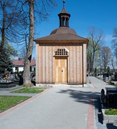 Zdjęcie nr 22: Kościół murowany z cegły, z użyciem zendrówki, na wysokim podmurowaniu z kamienia łupanego, jednonawowy, orientowany. 
Prezbiterium i nawa na planie prostokątów, nawa szersza i dłuższa od prezbiterium. Zakrystia na rzucie wydłużonego prostokąta przylega do wschodniej ściany prezbiterium, występując poza mury nawy. Prezbiterium od wschodu ujęte w narożach dwiema ukośnymi szkarpami, od południa jedną prostopadłą. Przy południowej ścianie nawy kruchta na planie kwadratu. Nawa w narożach ujęta szkarpami, od wschodu dwiema prostopadłymi, od zachodu ukośnymi. 
Prezbiterium dwuprzęsłowe, nakryte sklepieniem krzyżowo-żebrowym. Na zwornikach dwie tarcze z herbami Trzy Korony i Wieniawa. Zakrystia sklepiona kolebkowo. Nawa nakryta drewnianym stropem z kasetonami i rozetami. Kruchta sklepiona krzyżowo-żebrowo ze zwornikiem z tarczą z herbem Wieniawa. Otwór tęczowy w formie stojącego prostokąta zamkniętego łukiem ostrym. W zachodniej części nawy drewniany parapet chóru muzycznego wsparty na dwóch filarach. 
Fasada w jednej trzeciej wysokości odcięta kamiennym gzymsem kapnikowym, zakończona jodełkowym fryzem w partii muru, zwieńczona trójkątnym szczytem. Mur dekorowany zendrówką ułożoną „w zęby”, w partii szczytu w układzie rombowym. Na osi kamienny ostrołukowy portal o schodkowym nadprożu, dekorowanym krzyżującym się laskowaniem; węgary gładkie w jednej trzeciej wysokości przechodzące w piramidki i profilowanie powyżej. Nad portalem kamienna kwadratowa tablica, ujęta kamiennym obramieniem z tarczą z herbem Wieniawa. Ponad nią, na osi okulus w kamiennym obramieniu. 
Elewacje północna i południowa w części nawy w jednej trzeciej wysokości przedzielone kamiennym gzymsem kapnikowym, na zakończeniu ścian z gzymsem wieńczącym. Mur dekorowany zendrówką w układzie rombowym. Na elewacji południowej cztery okna w formie wydłużonego, stojącego prostokąta zamkniętego łukiem ostrym, w kamiennych obramieniach, podzielone laskowaniem. Południowa ściana prezbiterium zakończona gzymsem wieńczącym, w górnej części muru dekorowana zendrówką ułożoną „w zęby”. 
Szkarpy opinające nawę uskokowe, zwężające się ku górze, nakryte daszkami pulpitowymi. Szkarpy opinające prezbiterium nakryte daszkami pulpitowymi, podzielone gzymsami kapnikowymi. 
Kruchta od strony wschodniej i zachodniej podzielona kamiennym gzymsem kapnikowym, od południa zakończona gzymsem wieńczącym. Na ścianie południowej kruchty kamienny, ostrołukowy portal, o schodkowym nadprożu, dekorowanym krzyżującym się laskowaniem; węgary gładkie, w jednej trzeciej wysokości przechodzące w piramidki i profilowanie powyżej. Nad portalem kamienna tarcza z herbem Wieniawa. 
Elewacja wschodnia zwieńczona trójkątnym szczytem, w którego partii mur dekorowany jest zendrówką w układzie rombowym. Na osi okno w formie wydłużonego, stojącego prostokąta zamkniętego łukiem ostrym, w kamiennym obramieniu, zamurowane w trzech piątych wysokości, zakończone daszkiem pulpitowym. W dolnej części okna znajduje się ogrójec. 
Nawa i prezbiterium nakryte osobnymi blaszanymi dachami dwuspadowymi, kruchta i zakrystia pulpitowymi. Nad nawą blaszana wieżyczka na sygnaturkę z latarnią i hełmem baniastym.





