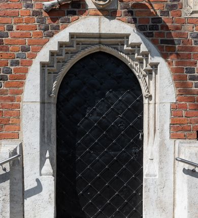 Zdjęcie nr 83: Kościół murowany z cegły, z użyciem zendrówki, na wysokim podmurowaniu z kamienia łupanego, jednonawowy, orientowany. 
Prezbiterium i nawa na planie prostokątów, nawa szersza i dłuższa od prezbiterium. Zakrystia na rzucie wydłużonego prostokąta przylega do wschodniej ściany prezbiterium, występując poza mury nawy. Prezbiterium od wschodu ujęte w narożach dwiema ukośnymi szkarpami, od południa jedną prostopadłą. Przy południowej ścianie nawy kruchta na planie kwadratu. Nawa w narożach ujęta szkarpami, od wschodu dwiema prostopadłymi, od zachodu ukośnymi. 
Prezbiterium dwuprzęsłowe, nakryte sklepieniem krzyżowo-żebrowym. Na zwornikach dwie tarcze z herbami Trzy Korony i Wieniawa. Zakrystia sklepiona kolebkowo. Nawa nakryta drewnianym stropem z kasetonami i rozetami. Kruchta sklepiona krzyżowo-żebrowo ze zwornikiem z tarczą z herbem Wieniawa. Otwór tęczowy w formie stojącego prostokąta zamkniętego łukiem ostrym. W zachodniej części nawy drewniany parapet chóru muzycznego wsparty na dwóch filarach. 
Fasada w jednej trzeciej wysokości odcięta kamiennym gzymsem kapnikowym, zakończona jodełkowym fryzem w partii muru, zwieńczona trójkątnym szczytem. Mur dekorowany zendrówką ułożoną „w zęby”, w partii szczytu w układzie rombowym. Na osi kamienny ostrołukowy portal o schodkowym nadprożu, dekorowanym krzyżującym się laskowaniem; węgary gładkie w jednej trzeciej wysokości przechodzące w piramidki i profilowanie powyżej. Nad portalem kamienna kwadratowa tablica, ujęta kamiennym obramieniem z tarczą z herbem Wieniawa. Ponad nią, na osi okulus w kamiennym obramieniu. 
Elewacje północna i południowa w części nawy w jednej trzeciej wysokości przedzielone kamiennym gzymsem kapnikowym, na zakończeniu ścian z gzymsem wieńczącym. Mur dekorowany zendrówką w układzie rombowym. Na elewacji południowej cztery okna w formie wydłużonego, stojącego prostokąta zamkniętego łukiem ostrym, w kamiennych obramieniach, podzielone laskowaniem. Południowa ściana prezbiterium zakończona gzymsem wieńczącym, w górnej części muru dekorowana zendrówką ułożoną „w zęby”. 
Szkarpy opinające nawę uskokowe, zwężające się ku górze, nakryte daszkami pulpitowymi. Szkarpy opinające prezbiterium nakryte daszkami pulpitowymi, podzielone gzymsami kapnikowymi. 
Kruchta od strony wschodniej i zachodniej podzielona kamiennym gzymsem kapnikowym, od południa zakończona gzymsem wieńczącym. Na ścianie południowej kruchty kamienny, ostrołukowy portal, o schodkowym nadprożu, dekorowanym krzyżującym się laskowaniem; węgary gładkie, w jednej trzeciej wysokości przechodzące w piramidki i profilowanie powyżej. Nad portalem kamienna tarcza z herbem Wieniawa. 
Elewacja wschodnia zwieńczona trójkątnym szczytem, w którego partii mur dekorowany jest zendrówką w układzie rombowym. Na osi okno w formie wydłużonego, stojącego prostokąta zamkniętego łukiem ostrym, w kamiennym obramieniu, zamurowane w trzech piątych wysokości, zakończone daszkiem pulpitowym. W dolnej części okna znajduje się ogrójec. 
Nawa i prezbiterium nakryte osobnymi blaszanymi dachami dwuspadowymi, kruchta i zakrystia pulpitowymi. Nad nawą blaszana wieżyczka na sygnaturkę z latarnią i hełmem baniastym.





