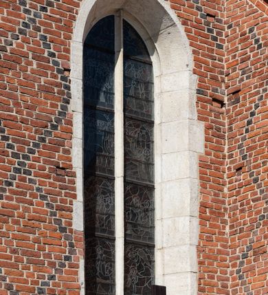 Zdjęcie nr 86: Kościół murowany z cegły, z użyciem zendrówki, na wysokim podmurowaniu z kamienia łupanego, jednonawowy, orientowany. 
Prezbiterium i nawa na planie prostokątów, nawa szersza i dłuższa od prezbiterium. Zakrystia na rzucie wydłużonego prostokąta przylega do wschodniej ściany prezbiterium, występując poza mury nawy. Prezbiterium od wschodu ujęte w narożach dwiema ukośnymi szkarpami, od południa jedną prostopadłą. Przy południowej ścianie nawy kruchta na planie kwadratu. Nawa w narożach ujęta szkarpami, od wschodu dwiema prostopadłymi, od zachodu ukośnymi. 
Prezbiterium dwuprzęsłowe, nakryte sklepieniem krzyżowo-żebrowym. Na zwornikach dwie tarcze z herbami Trzy Korony i Wieniawa. Zakrystia sklepiona kolebkowo. Nawa nakryta drewnianym stropem z kasetonami i rozetami. Kruchta sklepiona krzyżowo-żebrowo ze zwornikiem z tarczą z herbem Wieniawa. Otwór tęczowy w formie stojącego prostokąta zamkniętego łukiem ostrym. W zachodniej części nawy drewniany parapet chóru muzycznego wsparty na dwóch filarach. 
Fasada w jednej trzeciej wysokości odcięta kamiennym gzymsem kapnikowym, zakończona jodełkowym fryzem w partii muru, zwieńczona trójkątnym szczytem. Mur dekorowany zendrówką ułożoną „w zęby”, w partii szczytu w układzie rombowym. Na osi kamienny ostrołukowy portal o schodkowym nadprożu, dekorowanym krzyżującym się laskowaniem; węgary gładkie w jednej trzeciej wysokości przechodzące w piramidki i profilowanie powyżej. Nad portalem kamienna kwadratowa tablica, ujęta kamiennym obramieniem z tarczą z herbem Wieniawa. Ponad nią, na osi okulus w kamiennym obramieniu. 
Elewacje północna i południowa w części nawy w jednej trzeciej wysokości przedzielone kamiennym gzymsem kapnikowym, na zakończeniu ścian z gzymsem wieńczącym. Mur dekorowany zendrówką w układzie rombowym. Na elewacji południowej cztery okna w formie wydłużonego, stojącego prostokąta zamkniętego łukiem ostrym, w kamiennych obramieniach, podzielone laskowaniem. Południowa ściana prezbiterium zakończona gzymsem wieńczącym, w górnej części muru dekorowana zendrówką ułożoną „w zęby”. 
Szkarpy opinające nawę uskokowe, zwężające się ku górze, nakryte daszkami pulpitowymi. Szkarpy opinające prezbiterium nakryte daszkami pulpitowymi, podzielone gzymsami kapnikowymi. 
Kruchta od strony wschodniej i zachodniej podzielona kamiennym gzymsem kapnikowym, od południa zakończona gzymsem wieńczącym. Na ścianie południowej kruchty kamienny, ostrołukowy portal, o schodkowym nadprożu, dekorowanym krzyżującym się laskowaniem; węgary gładkie, w jednej trzeciej wysokości przechodzące w piramidki i profilowanie powyżej. Nad portalem kamienna tarcza z herbem Wieniawa. 
Elewacja wschodnia zwieńczona trójkątnym szczytem, w którego partii mur dekorowany jest zendrówką w układzie rombowym. Na osi okno w formie wydłużonego, stojącego prostokąta zamkniętego łukiem ostrym, w kamiennym obramieniu, zamurowane w trzech piątych wysokości, zakończone daszkiem pulpitowym. W dolnej części okna znajduje się ogrójec. 
Nawa i prezbiterium nakryte osobnymi blaszanymi dachami dwuspadowymi, kruchta i zakrystia pulpitowymi. Nad nawą blaszana wieżyczka na sygnaturkę z latarnią i hełmem baniastym.





