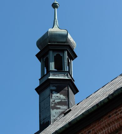 Zdjęcie nr 93: Kościół murowany z cegły, z użyciem zendrówki, na wysokim podmurowaniu z kamienia łupanego, jednonawowy, orientowany. 
Prezbiterium i nawa na planie prostokątów, nawa szersza i dłuższa od prezbiterium. Zakrystia na rzucie wydłużonego prostokąta przylega do wschodniej ściany prezbiterium, występując poza mury nawy. Prezbiterium od wschodu ujęte w narożach dwiema ukośnymi szkarpami, od południa jedną prostopadłą. Przy południowej ścianie nawy kruchta na planie kwadratu. Nawa w narożach ujęta szkarpami, od wschodu dwiema prostopadłymi, od zachodu ukośnymi. 
Prezbiterium dwuprzęsłowe, nakryte sklepieniem krzyżowo-żebrowym. Na zwornikach dwie tarcze z herbami Trzy Korony i Wieniawa. Zakrystia sklepiona kolebkowo. Nawa nakryta drewnianym stropem z kasetonami i rozetami. Kruchta sklepiona krzyżowo-żebrowo ze zwornikiem z tarczą z herbem Wieniawa. Otwór tęczowy w formie stojącego prostokąta zamkniętego łukiem ostrym. W zachodniej części nawy drewniany parapet chóru muzycznego wsparty na dwóch filarach. 
Fasada w jednej trzeciej wysokości odcięta kamiennym gzymsem kapnikowym, zakończona jodełkowym fryzem w partii muru, zwieńczona trójkątnym szczytem. Mur dekorowany zendrówką ułożoną „w zęby”, w partii szczytu w układzie rombowym. Na osi kamienny ostrołukowy portal o schodkowym nadprożu, dekorowanym krzyżującym się laskowaniem; węgary gładkie w jednej trzeciej wysokości przechodzące w piramidki i profilowanie powyżej. Nad portalem kamienna kwadratowa tablica, ujęta kamiennym obramieniem z tarczą z herbem Wieniawa. Ponad nią, na osi okulus w kamiennym obramieniu. 
Elewacje północna i południowa w części nawy w jednej trzeciej wysokości przedzielone kamiennym gzymsem kapnikowym, na zakończeniu ścian z gzymsem wieńczącym. Mur dekorowany zendrówką w układzie rombowym. Na elewacji południowej cztery okna w formie wydłużonego, stojącego prostokąta zamkniętego łukiem ostrym, w kamiennych obramieniach, podzielone laskowaniem. Południowa ściana prezbiterium zakończona gzymsem wieńczącym, w górnej części muru dekorowana zendrówką ułożoną „w zęby”. 
Szkarpy opinające nawę uskokowe, zwężające się ku górze, nakryte daszkami pulpitowymi. Szkarpy opinające prezbiterium nakryte daszkami pulpitowymi, podzielone gzymsami kapnikowymi. 
Kruchta od strony wschodniej i zachodniej podzielona kamiennym gzymsem kapnikowym, od południa zakończona gzymsem wieńczącym. Na ścianie południowej kruchty kamienny, ostrołukowy portal, o schodkowym nadprożu, dekorowanym krzyżującym się laskowaniem; węgary gładkie, w jednej trzeciej wysokości przechodzące w piramidki i profilowanie powyżej. Nad portalem kamienna tarcza z herbem Wieniawa. 
Elewacja wschodnia zwieńczona trójkątnym szczytem, w którego partii mur dekorowany jest zendrówką w układzie rombowym. Na osi okno w formie wydłużonego, stojącego prostokąta zamkniętego łukiem ostrym, w kamiennym obramieniu, zamurowane w trzech piątych wysokości, zakończone daszkiem pulpitowym. W dolnej części okna znajduje się ogrójec. 
Nawa i prezbiterium nakryte osobnymi blaszanymi dachami dwuspadowymi, kruchta i zakrystia pulpitowymi. Nad nawą blaszana wieżyczka na sygnaturkę z latarnią i hełmem baniastym.






