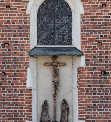 Zdjęcie nr 113: Kościół murowany z cegły, z użyciem zendrówki, na wysokim podmurowaniu z kamienia łupanego, jednonawowy, orientowany. 
Prezbiterium i nawa na planie prostokątów, nawa szersza i dłuższa od prezbiterium. Zakrystia na rzucie wydłużonego prostokąta przylega do wschodniej ściany prezbiterium, występując poza mury nawy. Prezbiterium od wschodu ujęte w narożach dwiema ukośnymi szkarpami, od południa jedną prostopadłą. Przy południowej ścianie nawy kruchta na planie kwadratu. Nawa w narożach ujęta szkarpami, od wschodu dwiema prostopadłymi, od zachodu ukośnymi. 
Prezbiterium dwuprzęsłowe, nakryte sklepieniem krzyżowo-żebrowym. Na zwornikach dwie tarcze z herbami Trzy Korony i Wieniawa. Zakrystia sklepiona kolebkowo. Nawa nakryta drewnianym stropem z kasetonami i rozetami. Kruchta sklepiona krzyżowo-żebrowo ze zwornikiem z tarczą z herbem Wieniawa. Otwór tęczowy w formie stojącego prostokąta zamkniętego łukiem ostrym. W zachodniej części nawy drewniany parapet chóru muzycznego wsparty na dwóch filarach. 
Fasada w jednej trzeciej wysokości odcięta kamiennym gzymsem kapnikowym, zakończona jodełkowym fryzem w partii muru, zwieńczona trójkątnym szczytem. Mur dekorowany zendrówką ułożoną „w zęby”, w partii szczytu w układzie rombowym. Na osi kamienny ostrołukowy portal o schodkowym nadprożu, dekorowanym krzyżującym się laskowaniem; węgary gładkie w jednej trzeciej wysokości przechodzące w piramidki i profilowanie powyżej. Nad portalem kamienna kwadratowa tablica, ujęta kamiennym obramieniem z tarczą z herbem Wieniawa. Ponad nią, na osi okulus w kamiennym obramieniu. 
Elewacje północna i południowa w części nawy w jednej trzeciej wysokości przedzielone kamiennym gzymsem kapnikowym, na zakończeniu ścian z gzymsem wieńczącym. Mur dekorowany zendrówką w układzie rombowym. Na elewacji południowej cztery okna w formie wydłużonego, stojącego prostokąta zamkniętego łukiem ostrym, w kamiennych obramieniach, podzielone laskowaniem. Południowa ściana prezbiterium zakończona gzymsem wieńczącym, w górnej części muru dekorowana zendrówką ułożoną „w zęby”. 
Szkarpy opinające nawę uskokowe, zwężające się ku górze, nakryte daszkami pulpitowymi. Szkarpy opinające prezbiterium nakryte daszkami pulpitowymi, podzielone gzymsami kapnikowymi. 
Kruchta od strony wschodniej i zachodniej podzielona kamiennym gzymsem kapnikowym, od południa zakończona gzymsem wieńczącym. Na ścianie południowej kruchty kamienny, ostrołukowy portal, o schodkowym nadprożu, dekorowanym krzyżującym się laskowaniem; węgary gładkie, w jednej trzeciej wysokości przechodzące w piramidki i profilowanie powyżej. Nad portalem kamienna tarcza z herbem Wieniawa. 
Elewacja wschodnia zwieńczona trójkątnym szczytem, w którego partii mur dekorowany jest zendrówką w układzie rombowym. Na osi okno w formie wydłużonego, stojącego prostokąta zamkniętego łukiem ostrym, w kamiennym obramieniu, zamurowane w trzech piątych wysokości, zakończone daszkiem pulpitowym. W dolnej części okna znajduje się ogrójec. 
Nawa i prezbiterium nakryte osobnymi blaszanymi dachami dwuspadowymi, kruchta i zakrystia pulpitowymi. Nad nawą blaszana wieżyczka na sygnaturkę z latarnią i hełmem baniastym.





