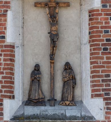 Zdjęcie nr 116: Kościół murowany z cegły, z użyciem zendrówki, na wysokim podmurowaniu z kamienia łupanego, jednonawowy, orientowany. 
Prezbiterium i nawa na planie prostokątów, nawa szersza i dłuższa od prezbiterium. Zakrystia na rzucie wydłużonego prostokąta przylega do wschodniej ściany prezbiterium, występując poza mury nawy. Prezbiterium od wschodu ujęte w narożach dwiema ukośnymi szkarpami, od południa jedną prostopadłą. Przy południowej ścianie nawy kruchta na planie kwadratu. Nawa w narożach ujęta szkarpami, od wschodu dwiema prostopadłymi, od zachodu ukośnymi. 
Prezbiterium dwuprzęsłowe, nakryte sklepieniem krzyżowo-żebrowym. Na zwornikach dwie tarcze z herbami Trzy Korony i Wieniawa. Zakrystia sklepiona kolebkowo. Nawa nakryta drewnianym stropem z kasetonami i rozetami. Kruchta sklepiona krzyżowo-żebrowo ze zwornikiem z tarczą z herbem Wieniawa. Otwór tęczowy w formie stojącego prostokąta zamkniętego łukiem ostrym. W zachodniej części nawy drewniany parapet chóru muzycznego wsparty na dwóch filarach. 
Fasada w jednej trzeciej wysokości odcięta kamiennym gzymsem kapnikowym, zakończona jodełkowym fryzem w partii muru, zwieńczona trójkątnym szczytem. Mur dekorowany zendrówką ułożoną „w zęby”, w partii szczytu w układzie rombowym. Na osi kamienny ostrołukowy portal o schodkowym nadprożu, dekorowanym krzyżującym się laskowaniem; węgary gładkie w jednej trzeciej wysokości przechodzące w piramidki i profilowanie powyżej. Nad portalem kamienna kwadratowa tablica, ujęta kamiennym obramieniem z tarczą z herbem Wieniawa. Ponad nią, na osi okulus w kamiennym obramieniu. 
Elewacje północna i południowa w części nawy w jednej trzeciej wysokości przedzielone kamiennym gzymsem kapnikowym, na zakończeniu ścian z gzymsem wieńczącym. Mur dekorowany zendrówką w układzie rombowym. Na elewacji południowej cztery okna w formie wydłużonego, stojącego prostokąta zamkniętego łukiem ostrym, w kamiennych obramieniach, podzielone laskowaniem. Południowa ściana prezbiterium zakończona gzymsem wieńczącym, w górnej części muru dekorowana zendrówką ułożoną „w zęby”. 
Szkarpy opinające nawę uskokowe, zwężające się ku górze, nakryte daszkami pulpitowymi. Szkarpy opinające prezbiterium nakryte daszkami pulpitowymi, podzielone gzymsami kapnikowymi. 
Kruchta od strony wschodniej i zachodniej podzielona kamiennym gzymsem kapnikowym, od południa zakończona gzymsem wieńczącym. Na ścianie południowej kruchty kamienny, ostrołukowy portal, o schodkowym nadprożu, dekorowanym krzyżującym się laskowaniem; węgary gładkie, w jednej trzeciej wysokości przechodzące w piramidki i profilowanie powyżej. Nad portalem kamienna tarcza z herbem Wieniawa. 
Elewacja wschodnia zwieńczona trójkątnym szczytem, w którego partii mur dekorowany jest zendrówką w układzie rombowym. Na osi okno w formie wydłużonego, stojącego prostokąta zamkniętego łukiem ostrym, w kamiennym obramieniu, zamurowane w trzech piątych wysokości, zakończone daszkiem pulpitowym. W dolnej części okna znajduje się ogrójec. 
Nawa i prezbiterium nakryte osobnymi blaszanymi dachami dwuspadowymi, kruchta i zakrystia pulpitowymi. Nad nawą blaszana wieżyczka na sygnaturkę z latarnią i hełmem baniastym.





