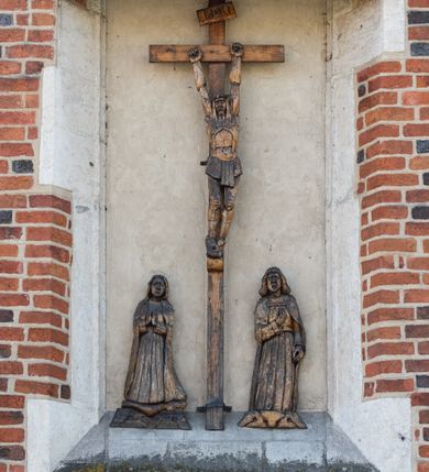 Zdjęcie nr 114: Kościół murowany z cegły, z użyciem zendrówki, na wysokim podmurowaniu z kamienia łupanego, jednonawowy, orientowany. 
Prezbiterium i nawa na planie prostokątów, nawa szersza i dłuższa od prezbiterium. Zakrystia na rzucie wydłużonego prostokąta przylega do wschodniej ściany prezbiterium, występując poza mury nawy. Prezbiterium od wschodu ujęte w narożach dwiema ukośnymi szkarpami, od południa jedną prostopadłą. Przy południowej ścianie nawy kruchta na planie kwadratu. Nawa w narożach ujęta szkarpami, od wschodu dwiema prostopadłymi, od zachodu ukośnymi. 
Prezbiterium dwuprzęsłowe, nakryte sklepieniem krzyżowo-żebrowym. Na zwornikach dwie tarcze z herbami Trzy Korony i Wieniawa. Zakrystia sklepiona kolebkowo. Nawa nakryta drewnianym stropem z kasetonami i rozetami. Kruchta sklepiona krzyżowo-żebrowo ze zwornikiem z tarczą z herbem Wieniawa. Otwór tęczowy w formie stojącego prostokąta zamkniętego łukiem ostrym. W zachodniej części nawy drewniany parapet chóru muzycznego wsparty na dwóch filarach. 
Fasada w jednej trzeciej wysokości odcięta kamiennym gzymsem kapnikowym, zakończona jodełkowym fryzem w partii muru, zwieńczona trójkątnym szczytem. Mur dekorowany zendrówką ułożoną „w zęby”, w partii szczytu w układzie rombowym. Na osi kamienny ostrołukowy portal o schodkowym nadprożu, dekorowanym krzyżującym się laskowaniem; węgary gładkie w jednej trzeciej wysokości przechodzące w piramidki i profilowanie powyżej. Nad portalem kamienna kwadratowa tablica, ujęta kamiennym obramieniem z tarczą z herbem Wieniawa. Ponad nią, na osi okulus w kamiennym obramieniu. 
Elewacje północna i południowa w części nawy w jednej trzeciej wysokości przedzielone kamiennym gzymsem kapnikowym, na zakończeniu ścian z gzymsem wieńczącym. Mur dekorowany zendrówką w układzie rombowym. Na elewacji południowej cztery okna w formie wydłużonego, stojącego prostokąta zamkniętego łukiem ostrym, w kamiennych obramieniach, podzielone laskowaniem. Południowa ściana prezbiterium zakończona gzymsem wieńczącym, w górnej części muru dekorowana zendrówką ułożoną „w zęby”. 
Szkarpy opinające nawę uskokowe, zwężające się ku górze, nakryte daszkami pulpitowymi. Szkarpy opinające prezbiterium nakryte daszkami pulpitowymi, podzielone gzymsami kapnikowymi. 
Kruchta od strony wschodniej i zachodniej podzielona kamiennym gzymsem kapnikowym, od południa zakończona gzymsem wieńczącym. Na ścianie południowej kruchty kamienny, ostrołukowy portal, o schodkowym nadprożu, dekorowanym krzyżującym się laskowaniem; węgary gładkie, w jednej trzeciej wysokości przechodzące w piramidki i profilowanie powyżej. Nad portalem kamienna tarcza z herbem Wieniawa. 
Elewacja wschodnia zwieńczona trójkątnym szczytem, w którego partii mur dekorowany jest zendrówką w układzie rombowym. Na osi okno w formie wydłużonego, stojącego prostokąta zamkniętego łukiem ostrym, w kamiennym obramieniu, zamurowane w trzech piątych wysokości, zakończone daszkiem pulpitowym. W dolnej części okna znajduje się ogrójec. 
Nawa i prezbiterium nakryte osobnymi blaszanymi dachami dwuspadowymi, kruchta i zakrystia pulpitowymi. Nad nawą blaszana wieżyczka na sygnaturkę z latarnią i hełmem baniastym.





