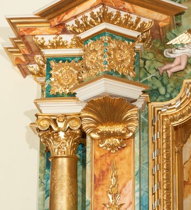 Zdjęcie nr 10: Ołtarz przyścienny, architektoniczny, jednoosiowy, jednokondygnacyjny ze zwieńczeniem. Mensa prostopadłościenna, w antepedium prostokątna płycina ujęta parą kolumienek wspartych na cokołach, ozdobiona aplikowanym krzyżem i dwiema ukośnie spiętymi gałązkami z liśćmi i kwiatami. Retabulum ustawione na wysokim, dwustrefowym cokole, zamkniętym wyłamanym i profilowanym gzymsem. Nastawa ołtarzowa ujęta parą filarów i kolumn ustawionych na tle pilastrów. Trzony kolumn do jednej trzeciej wysokości spiralnie skręcone, powyżej gładkie z grawerowaną wicią winorośli; trzony pilastrów wypełnione prostokątnymi płycinami ze stylizowaną wicią roślinną; kapitele podpór korynckie. Podpory wspierają wyłamane belkowanie, przerwane nad częścią środkową, zamknięte wydatnym, profilowanym gzymsem. W polu środkowym nastawy zamknięta trójbocznie wnęka ze zdwojoną ramą w kształcie stojącego prostokąta, zamkniętego łukiem wklęsło-wypukłym z uskokami z rzeźbą Matki Boskiej z Dzieciątkiem oraz obrazami „Św. Józef” oraz „Św. Agnieszka” na zasuwie. Na osi filarów, w partii belkowania ustawione są pod kątem imposty, podtrzymywane przez płaskie i stylizowane muszle; pośrodku gołębica Ducha Świętego na tle promienistej glorii, a poniżej dwie płaskorzeźbione figury aniołów.  Zwieńczenie w kształcie stojącego prostokąta, ujęte parą ukośnie dostawionych filarów, wspierających wyłamane belkowanie. W polu środkowym owalny obraz „Nauczanie Marii”. Na szczycie zwieńczenia figura św. Michała Archanioła. Dekoracja ornamentalna: przednie ścianki cokołów dekorowane rozetami, po bokach cokołów owalne kartusze ujęte stylizowanymi liśćmi akantu; fryz dekorowany rozetami kwiatowymi; po bokach zwieńczenia uszaki formowane z ażurowej wici roślinnej. Całość struktury ołtarza pokryta marmoryzacją zielono-niebieską; w dolnej części cokołu, w płycinach i w partiach belkowania w kolorze czerwono-pomarańczowym. Detale oraz profilowania pozłacane i posrebrzane. 
