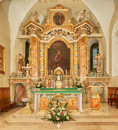 Zdjęcie nr 2: Obraz w kształcie stojącego prostokąta z przedstawieniem wizji św. Małgorzaty Marii Alacoque. Po prawej stronie kompozycji ukazana jest klęcząca św. Małgorzata Maria Alacoque, zwrócona trzy czwarte w prawo ze złożonymi w geście modlitwy dłońmi uniesionymi na lewą stronę, twarz widoczna z lewego profilu. Ubrana jest w czarny habit przepasany w talii z różańcem przy boku, wokół twarzy ma białą podwikę, na głowie czarny welon, a wokół niej złoty i kolisty nimb. Po lewej stronie obrazu stoi Chrystus na czerwonym podeście, wychodzący z obłoku, zwrócony trzy czwarte w lewo z prawą ręką opuszczoną w dół, a lewą ukazujący gorejące na piersi serce, głowa delikatnie pochylona. Twarz ma podłużną, okoloną brodą, z długim nosem i przymkniętymi oczami, włosy długie i bujne, zawinięte puklami do tyłu; wokół głowy ma złoty i kolisty nimb. Chrystus ubrany jest w jasnoczerwoną suknię oraz ciemnoniebieski płaszcz. Na jego piersi ukazane jest gorejące serce w glorii, otoczone koroną cierniową. Na dłoniach ma widoczne ślady po gwoździach z wychodzącymi z nich małymi promieniami. Całość ukazana jest we wnętrzu architektonicznym. Przed podestem leży dywan, bogato dekorowany geometrycznym wzorem. Po prawej stronie widoczna jest czarno-biała kamienna posadzka, w oddali klęcznik, a następnie niewielki ołtarzyk z tabernakulum i sześcioma lichtarzami, nakryty białym obrusem i z barankiem paschalnym na antependium. W górnej części obrazu, po prawej stronie widoczny jest w popiersiu mały, półnagi aniołek z kielichem z hostią w dłoniach.  Chrystus ukazany jest na tle ciemnej ściany. 
 