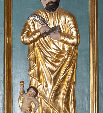 Zdjęcie nr 9: Ambona przyścienna, wisząca, z dostępem od zakrystii. Kosz na planie czterech boków z sześcioboku, na cokole w formie spłaszczonego wałka, z podwieszonym niewielkim cokolikiem zakończonym szyszką. Ścianki wydzielone pilastrami o kanelowanych trzonach, na cokołach, dźwigającymi parapet w formie gzymsu, wyłamany na ich osi. W polach ścianek płyciny o kształcie stojącego prostokąta z płaskorzeźbionymi przedstawieniami czterech ewangelistów. Zaplecek w formie wydłużonego, stojącego prostokąta, ujętego pilastrami o kanelowanych trzonach, zakończonych konsolami dekorowanymi liściem akantu, dźwigającymi imposty oraz przerwany, półokrągły przyczółek. W polu zaplecka drzwiczki do zakrystii, zdobione dwiema arkadami; ponad nimi płaskorzeźbione tablice praw. Baldachim na planie analogicznym względem kosza, w formie kopułki na wklęsłym, zwężającym się cokole dekorowanym płycinami, zakończonej latarnią z krzyżem na kuli. Brzeg w postaci gzymsu wyłamanego na osi podpór kosza, z siedzącymi nań puttami oraz z podwieszonym lambrekinem. Na podniebiu baldachimu rzeźbiona gołębica Ducha Świętego w glorii promienistej. 
Struktura polichromowana w kolorze szaro-niebieskim, profile i ornamentyka złocone.