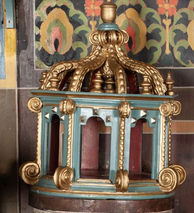 Zdjęcie nr 1: Chrzcielnica na schodkowej, trójstopniowej podstawie o kwadratowym przekroju. Trzon, w formie krótkiego walca, ujęty u góry półwałkiem o dekoracji sznurowej. Czara kielichowa z rytym zdobieniem w kształcie łezek oraz inskrypcją „R(oku) P(ańskiego) 1833”. Pokrywa drewniana w formie baldachimu na planie ośmioboku zwieńczona ośmioma kabłąkami ujmującymi szyszkę, podtrzymującymi okrąg z wazonem. Naroża baldachimu artykułowane taśmą o wolutowo zwiniętych końcach. Pokrywa malowana na brązowo, jasnoniebiesko i złoto. Kociołek w formie półkolistej misy z dwoma uchwytami. 