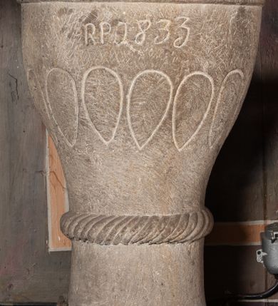 Zdjęcie nr 2: Chrzcielnica na schodkowej, trójstopniowej podstawie o kwadratowym przekroju. Trzon, w formie krótkiego walca, ujęty u góry półwałkiem o dekoracji sznurowej. Czara kielichowa z rytym zdobieniem w kształcie łezek oraz inskrypcją „R(oku) P(ańskiego) 1833”. Pokrywa drewniana w formie baldachimu na planie ośmioboku zwieńczona ośmioma kabłąkami ujmującymi szyszkę, podtrzymującymi okrąg z wazonem. Naroża baldachimu artykułowane taśmą o wolutowo zwiniętych końcach. Pokrywa malowana na brązowo, jasnoniebiesko i złoto. Kociołek w formie półkolistej misy z dwoma uchwytami. 