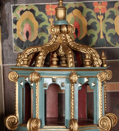 Zdjęcie nr 3: Chrzcielnica na schodkowej, trójstopniowej podstawie o kwadratowym przekroju. Trzon, w formie krótkiego walca, ujęty u góry półwałkiem o dekoracji sznurowej. Czara kielichowa z rytym zdobieniem w kształcie łezek oraz inskrypcją „R(oku) P(ańskiego) 1833”. Pokrywa drewniana w formie baldachimu na planie ośmioboku zwieńczona ośmioma kabłąkami ujmującymi szyszkę, podtrzymującymi okrąg z wazonem. Naroża baldachimu artykułowane taśmą o wolutowo zwiniętych końcach. Pokrywa malowana na brązowo, jasnoniebiesko i złoto. Kociołek w formie półkolistej misy z dwoma uchwytami. 