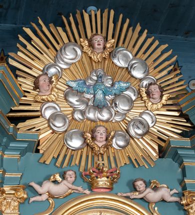 Zdjęcie nr 6: Ołtarz architektoniczny, jednokondygnacyjny, jednoosiowy, z bramkami i zwieńczeniem. Ołtarz kamienny, sarkofagowy, wklęsło-wypukły, na cokole. Mensa kamienna, o brzegu w formie profilowanego gzymsu. Tabernakulum drewniane, obite blachą, w postaci prostopadłościennej skrzynki, z wypukłą ścianką frontową, flankowane parą drewnianych kolumienek o kapitelach kompozytowych, na cokołach. Drzwiczki w formie kwadratu zamkniętego łukiem półkolistym, ujęte ramą z odlewaną dekoracją roślinną, w polu aplikowane, odlewane przedstawienie kielicha eucharystycznego w glorii promienistej na obłoku, z kłosami zbóż po bokach. Na tabernakulum osadzony tron wystawienia w formie prostopadłościanu, z wypukłą ścianką frontową oraz obrotową niszą ujętą profilowaną ramą, flankowany parą kolumienek o kapitelach kompozytowych, dźwigających imposty oraz przerwane w partii architrawu i fryzu belkowanie opasujące go z trzech stron. Na osi podpór przerwany, segmentowy przyczółek, ustawiony pod kątem. Na belkowaniu figurka Baranka Apokaliptycznego, leżącego na księdze na tle glorii promienistej. 
Retabulum na dwustrefowym cokole, w górnej partii zryzalitowanym przy brzegach, ujęte parą zwielokrotnionych pilastrów oraz stojącą przed nimi parą kolumn o kapitelach kompozytowych, ustawionych pod katem względem lica. Podpory dźwigają pełne belkowanie, wyłamane na ich osi, przerwane nad polem środkowym; na linii kolumn przerwany półokrągły przyczółek. W polu zwieńczenia gloria promienista z rzeźbioną gołębicą Ducha Świętego w otoczeniu obłoków i uskrzydlonych główek anielskich. W polu środkowym nisza w formie stojącego prostokąta zamkniętego łukiem segmentowym, w profilowanej ramie, z obrazem Matki Boskiej z Dzieciątkiem w aediculi. Bramki z przejściami w formie wydłużonego, stojącego prostokąta o wklęsłych górnych narożach, zamknięte dwoma spływami wolutowymi stanowiącymi podstawę dla cokołów na figury św. Piotra i św. Pawła. 
Cokoły kolumn dekorowane akantem. W polu środkowym, nad niszą para puttów podtrzymujących koronę; ramę flankują rocaillowe zwisy; u jej spodu palmety i rozety. Na brzegach belkowania wazony dekorowane plecionką i liśćmi. Kondygnacja ujęta uszami utworzonymi z wolut i liści palmowych. Spód cokołu wieńczącego bramki dekorowany muszlą; woluty zdobione kampanulami.
 Struktura polichromowana w kolorze szaro-niebieskim; kolumny, ramy, gloria, profile i ornamentyka złocone; obłoki srebrzone.
