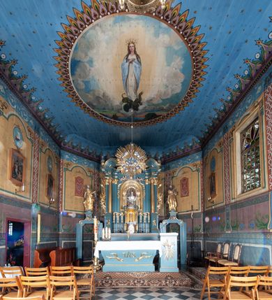 Zdjęcie nr 4: Ołtarz architektoniczny, jednokondygnacyjny, jednoosiowy, z bramkami i zwieńczeniem. Ołtarz kamienny, sarkofagowy, wklęsło-wypukły, na cokole. Mensa kamienna, o brzegu w formie profilowanego gzymsu. Tabernakulum drewniane, obite blachą, w postaci prostopadłościennej skrzynki, z wypukłą ścianką frontową, flankowane parą drewnianych kolumienek o kapitelach kompozytowych, na cokołach. Drzwiczki w formie kwadratu zamkniętego łukiem półkolistym, ujęte ramą z odlewaną dekoracją roślinną, w polu aplikowane, odlewane przedstawienie kielicha eucharystycznego w glorii promienistej na obłoku, z kłosami zbóż po bokach. Na tabernakulum osadzony tron wystawienia w formie prostopadłościanu, z wypukłą ścianką frontową oraz obrotową niszą ujętą profilowaną ramą, flankowany parą kolumienek o kapitelach kompozytowych, dźwigających imposty oraz przerwane w partii architrawu i fryzu belkowanie opasujące go z trzech stron. Na osi podpór przerwany, segmentowy przyczółek, ustawiony pod kątem. Na belkowaniu figurka Baranka Apokaliptycznego, leżącego na księdze na tle glorii promienistej. 
Retabulum na dwustrefowym cokole, w górnej partii zryzalitowanym przy brzegach, ujęte parą zwielokrotnionych pilastrów oraz stojącą przed nimi parą kolumn o kapitelach kompozytowych, ustawionych pod katem względem lica. Podpory dźwigają pełne belkowanie, wyłamane na ich osi, przerwane nad polem środkowym; na linii kolumn przerwany półokrągły przyczółek. W polu zwieńczenia gloria promienista z rzeźbioną gołębicą Ducha Świętego w otoczeniu obłoków i uskrzydlonych główek anielskich. W polu środkowym nisza w formie stojącego prostokąta zamkniętego łukiem segmentowym, w profilowanej ramie, z obrazem Matki Boskiej z Dzieciątkiem w aediculi. Bramki z przejściami w formie wydłużonego, stojącego prostokąta o wklęsłych górnych narożach, zamknięte dwoma spływami wolutowymi stanowiącymi podstawę dla cokołów na figury św. Piotra i św. Pawła. 
Cokoły kolumn dekorowane akantem. W polu środkowym, nad niszą para puttów podtrzymujących koronę; ramę flankują rocaillowe zwisy; u jej spodu palmety i rozety. Na brzegach belkowania wazony dekorowane plecionką i liśćmi. Kondygnacja ujęta uszami utworzonymi z wolut i liści palmowych. Spód cokołu wieńczącego bramki dekorowany muszlą; woluty zdobione kampanulami.
 Struktura polichromowana w kolorze szaro-niebieskim; kolumny, ramy, gloria, profile i ornamentyka złocone; obłoki srebrzone.
