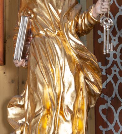 Zdjęcie nr 13: Ołtarz architektoniczny, jednokondygnacyjny, jednoosiowy, z bramkami i zwieńczeniem. Ołtarz kamienny, sarkofagowy, wklęsło-wypukły, na cokole. Mensa kamienna, o brzegu w formie profilowanego gzymsu. Tabernakulum drewniane, obite blachą, w postaci prostopadłościennej skrzynki, z wypukłą ścianką frontową, flankowane parą drewnianych kolumienek o kapitelach kompozytowych, na cokołach. Drzwiczki w formie kwadratu zamkniętego łukiem półkolistym, ujęte ramą z odlewaną dekoracją roślinną, w polu aplikowane, odlewane przedstawienie kielicha eucharystycznego w glorii promienistej na obłoku, z kłosami zbóż po bokach. Na tabernakulum osadzony tron wystawienia w formie prostopadłościanu, z wypukłą ścianką frontową oraz obrotową niszą ujętą profilowaną ramą, flankowany parą kolumienek o kapitelach kompozytowych, dźwigających imposty oraz przerwane w partii architrawu i fryzu belkowanie opasujące go z trzech stron. Na osi podpór przerwany, segmentowy przyczółek, ustawiony pod kątem. Na belkowaniu figurka Baranka Apokaliptycznego, leżącego na księdze na tle glorii promienistej. 
Retabulum na dwustrefowym cokole, w górnej partii zryzalitowanym przy brzegach, ujęte parą zwielokrotnionych pilastrów oraz stojącą przed nimi parą kolumn o kapitelach kompozytowych, ustawionych pod katem względem lica. Podpory dźwigają pełne belkowanie, wyłamane na ich osi, przerwane nad polem środkowym; na linii kolumn przerwany półokrągły przyczółek. W polu zwieńczenia gloria promienista z rzeźbioną gołębicą Ducha Świętego w otoczeniu obłoków i uskrzydlonych główek anielskich. W polu środkowym nisza w formie stojącego prostokąta zamkniętego łukiem segmentowym, w profilowanej ramie, z obrazem Matki Boskiej z Dzieciątkiem w aediculi. Bramki z przejściami w formie wydłużonego, stojącego prostokąta o wklęsłych górnych narożach, zamknięte dwoma spływami wolutowymi stanowiącymi podstawę dla cokołów na figury św. Piotra i św. Pawła. 
Cokoły kolumn dekorowane akantem. W polu środkowym, nad niszą para puttów podtrzymujących koronę; ramę flankują rocaillowe zwisy; u jej spodu palmety i rozety. Na brzegach belkowania wazony dekorowane plecionką i liśćmi. Kondygnacja ujęta uszami utworzonymi z wolut i liści palmowych. Spód cokołu wieńczącego bramki dekorowany muszlą; woluty zdobione kampanulami.
 Struktura polichromowana w kolorze szaro-niebieskim; kolumny, ramy, gloria, profile i ornamentyka złocone; obłoki srebrzone.
