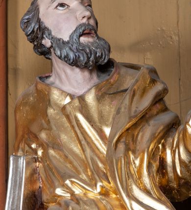 Zdjęcie nr 11: Ołtarz architektoniczny, jednokondygnacyjny, jednoosiowy, z bramkami i zwieńczeniem. Ołtarz kamienny, sarkofagowy, wklęsło-wypukły, na cokole. Mensa kamienna, o brzegu w formie profilowanego gzymsu. Tabernakulum drewniane, obite blachą, w postaci prostopadłościennej skrzynki, z wypukłą ścianką frontową, flankowane parą drewnianych kolumienek o kapitelach kompozytowych, na cokołach. Drzwiczki w formie kwadratu zamkniętego łukiem półkolistym, ujęte ramą z odlewaną dekoracją roślinną, w polu aplikowane, odlewane przedstawienie kielicha eucharystycznego w glorii promienistej na obłoku, z kłosami zbóż po bokach. Na tabernakulum osadzony tron wystawienia w formie prostopadłościanu, z wypukłą ścianką frontową oraz obrotową niszą ujętą profilowaną ramą, flankowany parą kolumienek o kapitelach kompozytowych, dźwigających imposty oraz przerwane w partii architrawu i fryzu belkowanie opasujące go z trzech stron. Na osi podpór przerwany, segmentowy przyczółek, ustawiony pod kątem. Na belkowaniu figurka Baranka Apokaliptycznego, leżącego na księdze na tle glorii promienistej. 
Retabulum na dwustrefowym cokole, w górnej partii zryzalitowanym przy brzegach, ujęte parą zwielokrotnionych pilastrów oraz stojącą przed nimi parą kolumn o kapitelach kompozytowych, ustawionych pod katem względem lica. Podpory dźwigają pełne belkowanie, wyłamane na ich osi, przerwane nad polem środkowym; na linii kolumn przerwany półokrągły przyczółek. W polu zwieńczenia gloria promienista z rzeźbioną gołębicą Ducha Świętego w otoczeniu obłoków i uskrzydlonych główek anielskich. W polu środkowym nisza w formie stojącego prostokąta zamkniętego łukiem segmentowym, w profilowanej ramie, z obrazem Matki Boskiej z Dzieciątkiem w aediculi. Bramki z przejściami w formie wydłużonego, stojącego prostokąta o wklęsłych górnych narożach, zamknięte dwoma spływami wolutowymi stanowiącymi podstawę dla cokołów na figury św. Piotra i św. Pawła. 
Cokoły kolumn dekorowane akantem. W polu środkowym, nad niszą para puttów podtrzymujących koronę; ramę flankują rocaillowe zwisy; u jej spodu palmety i rozety. Na brzegach belkowania wazony dekorowane plecionką i liśćmi. Kondygnacja ujęta uszami utworzonymi z wolut i liści palmowych. Spód cokołu wieńczącego bramki dekorowany muszlą; woluty zdobione kampanulami.
 Struktura polichromowana w kolorze szaro-niebieskim; kolumny, ramy, gloria, profile i ornamentyka złocone; obłoki srebrzone.
