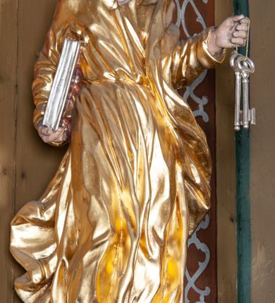 Zdjęcie nr 15: Ołtarz architektoniczny, jednokondygnacyjny, jednoosiowy, z bramkami i zwieńczeniem. Ołtarz kamienny, sarkofagowy, wklęsło-wypukły, na cokole. Mensa kamienna, o brzegu w formie profilowanego gzymsu. Tabernakulum drewniane, obite blachą, w postaci prostopadłościennej skrzynki, z wypukłą ścianką frontową, flankowane parą drewnianych kolumienek o kapitelach kompozytowych, na cokołach. Drzwiczki w formie kwadratu zamkniętego łukiem półkolistym, ujęte ramą z odlewaną dekoracją roślinną, w polu aplikowane, odlewane przedstawienie kielicha eucharystycznego w glorii promienistej na obłoku, z kłosami zbóż po bokach. Na tabernakulum osadzony tron wystawienia w formie prostopadłościanu, z wypukłą ścianką frontową oraz obrotową niszą ujętą profilowaną ramą, flankowany parą kolumienek o kapitelach kompozytowych, dźwigających imposty oraz przerwane w partii architrawu i fryzu belkowanie opasujące go z trzech stron. Na osi podpór przerwany, segmentowy przyczółek, ustawiony pod kątem. Na belkowaniu figurka Baranka Apokaliptycznego, leżącego na księdze na tle glorii promienistej. 
Retabulum na dwustrefowym cokole, w górnej partii zryzalitowanym przy brzegach, ujęte parą zwielokrotnionych pilastrów oraz stojącą przed nimi parą kolumn o kapitelach kompozytowych, ustawionych pod katem względem lica. Podpory dźwigają pełne belkowanie, wyłamane na ich osi, przerwane nad polem środkowym; na linii kolumn przerwany półokrągły przyczółek. W polu zwieńczenia gloria promienista z rzeźbioną gołębicą Ducha Świętego w otoczeniu obłoków i uskrzydlonych główek anielskich. W polu środkowym nisza w formie stojącego prostokąta zamkniętego łukiem segmentowym, w profilowanej ramie, z obrazem Matki Boskiej z Dzieciątkiem w aediculi. Bramki z przejściami w formie wydłużonego, stojącego prostokąta o wklęsłych górnych narożach, zamknięte dwoma spływami wolutowymi stanowiącymi podstawę dla cokołów na figury św. Piotra i św. Pawła. 
Cokoły kolumn dekorowane akantem. W polu środkowym, nad niszą para puttów podtrzymujących koronę; ramę flankują rocaillowe zwisy; u jej spodu palmety i rozety. Na brzegach belkowania wazony dekorowane plecionką i liśćmi. Kondygnacja ujęta uszami utworzonymi z wolut i liści palmowych. Spód cokołu wieńczącego bramki dekorowany muszlą; woluty zdobione kampanulami.
 Struktura polichromowana w kolorze szaro-niebieskim; kolumny, ramy, gloria, profile i ornamentyka złocone; obłoki srebrzone.
