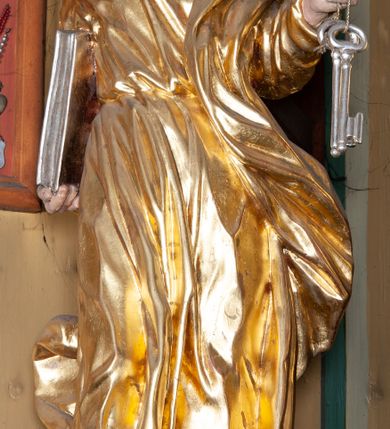 Zdjęcie nr 14: Ołtarz architektoniczny, jednokondygnacyjny, jednoosiowy, z bramkami i zwieńczeniem. Ołtarz kamienny, sarkofagowy, wklęsło-wypukły, na cokole. Mensa kamienna, o brzegu w formie profilowanego gzymsu. Tabernakulum drewniane, obite blachą, w postaci prostopadłościennej skrzynki, z wypukłą ścianką frontową, flankowane parą drewnianych kolumienek o kapitelach kompozytowych, na cokołach. Drzwiczki w formie kwadratu zamkniętego łukiem półkolistym, ujęte ramą z odlewaną dekoracją roślinną, w polu aplikowane, odlewane przedstawienie kielicha eucharystycznego w glorii promienistej na obłoku, z kłosami zbóż po bokach. Na tabernakulum osadzony tron wystawienia w formie prostopadłościanu, z wypukłą ścianką frontową oraz obrotową niszą ujętą profilowaną ramą, flankowany parą kolumienek o kapitelach kompozytowych, dźwigających imposty oraz przerwane w partii architrawu i fryzu belkowanie opasujące go z trzech stron. Na osi podpór przerwany, segmentowy przyczółek, ustawiony pod kątem. Na belkowaniu figurka Baranka Apokaliptycznego, leżącego na księdze na tle glorii promienistej. 
Retabulum na dwustrefowym cokole, w górnej partii zryzalitowanym przy brzegach, ujęte parą zwielokrotnionych pilastrów oraz stojącą przed nimi parą kolumn o kapitelach kompozytowych, ustawionych pod katem względem lica. Podpory dźwigają pełne belkowanie, wyłamane na ich osi, przerwane nad polem środkowym; na linii kolumn przerwany półokrągły przyczółek. W polu zwieńczenia gloria promienista z rzeźbioną gołębicą Ducha Świętego w otoczeniu obłoków i uskrzydlonych główek anielskich. W polu środkowym nisza w formie stojącego prostokąta zamkniętego łukiem segmentowym, w profilowanej ramie, z obrazem Matki Boskiej z Dzieciątkiem w aediculi. Bramki z przejściami w formie wydłużonego, stojącego prostokąta o wklęsłych górnych narożach, zamknięte dwoma spływami wolutowymi stanowiącymi podstawę dla cokołów na figury św. Piotra i św. Pawła. 
Cokoły kolumn dekorowane akantem. W polu środkowym, nad niszą para puttów podtrzymujących koronę; ramę flankują rocaillowe zwisy; u jej spodu palmety i rozety. Na brzegach belkowania wazony dekorowane plecionką i liśćmi. Kondygnacja ujęta uszami utworzonymi z wolut i liści palmowych. Spód cokołu wieńczącego bramki dekorowany muszlą; woluty zdobione kampanulami.
 Struktura polichromowana w kolorze szaro-niebieskim; kolumny, ramy, gloria, profile i ornamentyka złocone; obłoki srebrzone.
