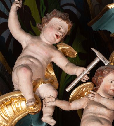 Zdjęcie nr 5: Ołtarz przyścienny, architektoniczny, jednoosiowy, jednokondygnacyjny ze zwieńczeniem. Mensa prostopadłościenna na niskim cokole. Nastawa ołtarzowa ustawiona na wysokim dwustrefowym cokole. Retabulum ujęte parą kolumn o stylizowanych, jońskich głowicach. Podpory wspierają belkowanie o wklęsłym wykroju, przerwane w części środkowej. Na gzymsie odcinki przyczółka o wolutowo skręconych końcach, skierowanych do wewnątrz. Zwieńczenie o wklęsłych bokach, zamknięte, dwoma stykającymi się wolutami z glorią promienistą. Pośrodku glorii symbol Opatrzności Bożej z IHS. Pole środkowe w formie prostokątnej wnęki ujętej ornamentem rocaille’owym. We wnęce rzeźbiony krucyfiks, zawieszony na tle malowanego pejzażu. Po bokach ołtarza, na osobnych konsolach ustawione figury Matki Boskiej po lewej oraz św. Jana Ewangelisty po prawej stronie. Po bokach zwieńczenia, na belkowaniu dwie pary rzeźbionych, uskrzydlonych aniołków. Boki wnęki środkowej dekorowane ornamentem rocaille’owym. Fontowe ścianki cokołów zdobione ażurowymi, wolutowo zwiniętymi liśćmi akantu. W zwieńczeniu obraz z przedstawieniem św. Michała Archanioła ujęty ramą formowaną z motywów „C” kształtnych. Struktura ołtarza malowana w kolorze niebieskim, boki mensy z prostokątnymi jasnobrązowymi płycinami, detal architektoniczny i profilowania złocone.

Figury uskrzydlonych aniołów pełnoplastyczne, ścięte z tyłu, siedzące na obłokach powyżej belkowania retabulum. Anioł po prawej stronie o szeroko rozłożonych rękach, głowie przechylonej w prawą stronę (h.). Anioł po lewej z rękoma uniesionymi, skierowanymi w prawo, głowa lekko pochylona, zwrócona w lewo. Figury niemal nagie, ze złotą przepaską wokół bioder. Twarze owalne o wydatnym czole okolone jasnobrązowymi włosami. Karnacja ciała w jasnokremowym odcieniu.