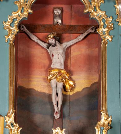 Zdjęcie nr 6: Ołtarz przyścienny, architektoniczny, jednoosiowy, jednokondygnacyjny ze zwieńczeniem. Mensa prostopadłościenna na niskim cokole. Nastawa ołtarzowa ustawiona na wysokim dwustrefowym cokole. Retabulum ujęte parą kolumn o stylizowanych, jońskich głowicach. Podpory wspierają belkowanie o wklęsłym wykroju, przerwane w części środkowej. Na gzymsie odcinki przyczółka o wolutowo skręconych końcach, skierowanych do wewnątrz. Zwieńczenie o wklęsłych bokach, zamknięte, dwoma stykającymi się wolutami z glorią promienistą. Pośrodku glorii symbol Opatrzności Bożej z IHS. Pole środkowe w formie prostokątnej wnęki ujętej ornamentem rocaille’owym. We wnęce rzeźbiony krucyfiks, zawieszony na tle malowanego pejzażu. Po bokach ołtarza, na osobnych konsolach ustawione figury Matki Boskiej po lewej oraz św. Jana Ewangelisty po prawej stronie. Po bokach zwieńczenia, na belkowaniu dwie pary rzeźbionych, uskrzydlonych aniołków. Boki wnęki środkowej dekorowane ornamentem rocaille’owym. Fontowe ścianki cokołów zdobione ażurowymi, wolutowo zwiniętymi liśćmi akantu. W zwieńczeniu obraz z przedstawieniem św. Michała Archanioła ujęty ramą formowaną z motywów „C” kształtnych. Struktura ołtarza malowana w kolorze niebieskim, boki mensy z prostokątnymi jasnobrązowymi płycinami, detal architektoniczny i profilowania złocone.

Figury uskrzydlonych aniołów pełnoplastyczne, ścięte z tyłu, siedzące na obłokach powyżej belkowania retabulum. Anioł po prawej stronie o szeroko rozłożonych rękach, głowie przechylonej w prawą stronę (h.). Anioł po lewej z rękoma uniesionymi, skierowanymi w prawo, głowa lekko pochylona, zwrócona w lewo. Figury niemal nagie, ze złotą przepaską wokół bioder. Twarze owalne o wydatnym czole okolone jasnobrązowymi włosami. Karnacja ciała w jasnokremowym odcieniu.