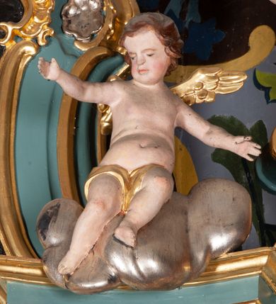 Zdjęcie nr 10: Ołtarz przyścienny, architektoniczny, jednoosiowy, jednokondygnacyjny ze zwieńczeniem. Mensa prostopadłościenna na niskim cokole. Nastawa ołtarzowa ustawiona na wysokim dwustrefowym cokole. Retabulum ujęte parą kolumn o stylizowanych, jońskich głowicach. Podpory wspierają belkowanie o wklęsłym wykroju, przerwane w części środkowej. Na gzymsie odcinki przyczółka o wolutowo skręconych końcach, skierowanych do wewnątrz. Zwieńczenie o wklęsłych bokach, zamknięte, dwoma stykającymi się wolutami z glorią promienistą. Pośrodku glorii symbol Opatrzności Bożej z IHS. Pole środkowe w formie prostokątnej wnęki ujętej ornamentem rocaille’owym. We wnęce rzeźbiony krucyfiks, zawieszony na tle malowanego pejzażu. Po bokach ołtarza, na osobnych konsolach ustawione figury Matki Boskiej po lewej oraz św. Jana Ewangelisty po prawej stronie. Po bokach zwieńczenia, na belkowaniu dwie pary rzeźbionych, uskrzydlonych aniołków. Boki wnęki środkowej dekorowane ornamentem rocaille’owym. Fontowe ścianki cokołów zdobione ażurowymi, wolutowo zwiniętymi liśćmi akantu. W zwieńczeniu obraz z przedstawieniem św. Michała Archanioła ujęty ramą formowaną z motywów „C” kształtnych. Struktura ołtarza malowana w kolorze niebieskim, boki mensy z prostokątnymi jasnobrązowymi płycinami, detal architektoniczny i profilowania złocone.

Figury uskrzydlonych aniołów pełnoplastyczne, ścięte z tyłu, siedzące na obłokach powyżej belkowania retabulum. Anioł po prawej stronie o szeroko rozłożonych rękach, głowie przechylonej w prawą stronę (h.). Anioł po lewej z rękoma uniesionymi, skierowanymi w prawo, głowa lekko pochylona, zwrócona w lewo. Figury niemal nagie, ze złotą przepaską wokół bioder. Twarze owalne o wydatnym czole okolone jasnobrązowymi włosami. Karnacja ciała w jasnokremowym odcieniu.