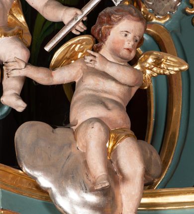 Zdjęcie nr 8: Ołtarz przyścienny, architektoniczny, jednoosiowy, jednokondygnacyjny ze zwieńczeniem. Mensa prostopadłościenna na niskim cokole. Nastawa ołtarzowa ustawiona na wysokim dwustrefowym cokole. Retabulum ujęte parą kolumn o stylizowanych, jońskich głowicach. Podpory wspierają belkowanie o wklęsłym wykroju, przerwane w części środkowej. Na gzymsie odcinki przyczółka o wolutowo skręconych końcach, skierowanych do wewnątrz. Zwieńczenie o wklęsłych bokach, zamknięte, dwoma stykającymi się wolutami z glorią promienistą. Pośrodku glorii symbol Opatrzności Bożej z IHS. Pole środkowe w formie prostokątnej wnęki ujętej ornamentem rocaille’owym. We wnęce rzeźbiony krucyfiks, zawieszony na tle malowanego pejzażu. Po bokach ołtarza, na osobnych konsolach ustawione figury Matki Boskiej po lewej oraz św. Jana Ewangelisty po prawej stronie. Po bokach zwieńczenia, na belkowaniu dwie pary rzeźbionych, uskrzydlonych aniołków. Boki wnęki środkowej dekorowane ornamentem rocaille’owym. Fontowe ścianki cokołów zdobione ażurowymi, wolutowo zwiniętymi liśćmi akantu. W zwieńczeniu obraz z przedstawieniem św. Michała Archanioła ujęty ramą formowaną z motywów „C” kształtnych. Struktura ołtarza malowana w kolorze niebieskim, boki mensy z prostokątnymi jasnobrązowymi płycinami, detal architektoniczny i profilowania złocone.

Figury uskrzydlonych aniołów pełnoplastyczne, ścięte z tyłu, siedzące na obłokach powyżej belkowania retabulum. Anioł po prawej stronie o szeroko rozłożonych rękach, głowie przechylonej w prawą stronę (h.). Anioł po lewej z rękoma uniesionymi, skierowanymi w prawo, głowa lekko pochylona, zwrócona w lewo. Figury niemal nagie, ze złotą przepaską wokół bioder. Twarze owalne o wydatnym czole okolone jasnobrązowymi włosami. Karnacja ciała w jasnokremowym odcieniu.