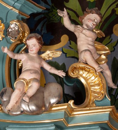 Zdjęcie nr 11: Ołtarz przyścienny, architektoniczny, jednoosiowy, jednokondygnacyjny ze zwieńczeniem. Mensa prostopadłościenna na niskim cokole. Nastawa ołtarzowa ustawiona na wysokim dwustrefowym cokole. Retabulum ujęte parą kolumn o stylizowanych, jońskich głowicach. Podpory wspierają belkowanie o wklęsłym wykroju, przerwane w części środkowej. Na gzymsie odcinki przyczółka o wolutowo skręconych końcach, skierowanych do wewnątrz. Zwieńczenie o wklęsłych bokach, zamknięte, dwoma stykającymi się wolutami z glorią promienistą. Pośrodku glorii symbol Opatrzności Bożej z IHS. Pole środkowe w formie prostokątnej wnęki ujętej ornamentem rocaille’owym. We wnęce rzeźbiony krucyfiks, zawieszony na tle malowanego pejzażu. Po bokach ołtarza, na osobnych konsolach ustawione figury Matki Boskiej po lewej oraz św. Jana Ewangelisty po prawej stronie. Po bokach zwieńczenia, na belkowaniu dwie pary rzeźbionych, uskrzydlonych aniołków. Boki wnęki środkowej dekorowane ornamentem rocaille’owym. Fontowe ścianki cokołów zdobione ażurowymi, wolutowo zwiniętymi liśćmi akantu. W zwieńczeniu obraz z przedstawieniem św. Michała Archanioła ujęty ramą formowaną z motywów „C” kształtnych. Struktura ołtarza malowana w kolorze niebieskim, boki mensy z prostokątnymi jasnobrązowymi płycinami, detal architektoniczny i profilowania złocone.

Figury uskrzydlonych aniołów pełnoplastyczne, ścięte z tyłu, siedzące na obłokach powyżej belkowania retabulum. Anioł po prawej stronie o szeroko rozłożonych rękach, głowie przechylonej w prawą stronę (h.). Anioł po lewej z rękoma uniesionymi, skierowanymi w prawo, głowa lekko pochylona, zwrócona w lewo. Figury niemal nagie, ze złotą przepaską wokół bioder. Twarze owalne o wydatnym czole okolone jasnobrązowymi włosami. Karnacja ciała w jasnokremowym odcieniu.