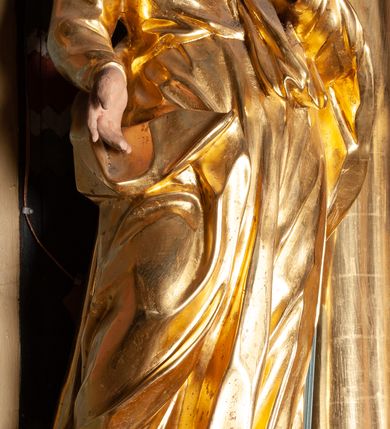 Zdjęcie nr 15: Ołtarz przyścienny, architektoniczny, jednoosiowy, jednokondygnacyjny ze zwieńczeniem. Mensa prostopadłościenna na niskim cokole. Nastawa ołtarzowa ustawiona na wysokim dwustrefowym cokole. Retabulum ujęte parą kolumn o stylizowanych, jońskich głowicach. Podpory wspierają belkowanie o wklęsłym wykroju, przerwane w części środkowej. Na gzymsie odcinki przyczółka o wolutowo skręconych końcach, skierowanych do wewnątrz. Zwieńczenie o wklęsłych bokach, zamknięte, dwoma stykającymi się wolutami z glorią promienistą. Pośrodku glorii symbol Opatrzności Bożej z IHS. Pole środkowe w formie prostokątnej wnęki ujętej ornamentem rocaille’owym. We wnęce rzeźbiony krucyfiks, zawieszony na tle malowanego pejzażu. Po bokach ołtarza, na osobnych konsolach ustawione figury Matki Boskiej po lewej oraz św. Jana Ewangelisty po prawej stronie. Po bokach zwieńczenia, na belkowaniu dwie pary rzeźbionych, uskrzydlonych aniołków. Boki wnęki środkowej dekorowane ornamentem rocaille’owym. Fontowe ścianki cokołów zdobione ażurowymi, wolutowo zwiniętymi liśćmi akantu. W zwieńczeniu obraz z przedstawieniem św. Michała Archanioła ujęty ramą formowaną z motywów „C” kształtnych. Struktura ołtarza malowana w kolorze niebieskim, boki mensy z prostokątnymi jasnobrązowymi płycinami, detal architektoniczny i profilowania złocone.

Figury uskrzydlonych aniołów pełnoplastyczne, ścięte z tyłu, siedzące na obłokach powyżej belkowania retabulum. Anioł po prawej stronie o szeroko rozłożonych rękach, głowie przechylonej w prawą stronę (h.). Anioł po lewej z rękoma uniesionymi, skierowanymi w prawo, głowa lekko pochylona, zwrócona w lewo. Figury niemal nagie, ze złotą przepaską wokół bioder. Twarze owalne o wydatnym czole okolone jasnobrązowymi włosami. Karnacja ciała w jasnokremowym odcieniu.