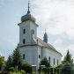 Zdjęcie nr 1: Murowany kościół otrzymał układ jednonawowej świątyni z węższym prezbiterium zwróconym ku północy i wieżą dostawioną do nawy od południa. Prezbiterium jest jednoprzęsłowe zakończone spłaszczoną apsydą. Na jego przedłużeniu usytuowano czworoboczną zakrystię. Prostokątna nawa jest trójprzęsłowa o zaokrąglonych narożnikach. Od frontu wzniesiono czworoboczną wieżę o ściętych narożnikach, flankowaną piętrowymi lokalnościami. Wysunięto ją lekko ku przodowi, gdzie przechodzi wklęsłymi płaszczyznami w boczne części fasady. Jej górne piętro nakryte cebulastym hełmem zostało opięte po bokach wolutami, obok których ustawiono kamienne klasycystyczne wazy. Elewacje zewnętrzne artykułowano podziałami ramowymi, zamykając wysokości ścian gzymsem gurtowy. Na końcu nawy na siodłowym dachu pokrytym blachą umieszczono czworoboczną wieżyczkę na sygnaturkę zwieńczoną cebulastym hełmem z krzyżem. Podobnym dachem nakryto prezbiterium. Wnętrze kościoła zostało rozczłonkowane lizenami z wklęsłymi półlizenami po bokach, ponad którymi rozciągnięto odcinki belkowania. Całość nakryto sklepieniem żaglastym na zdwojonych gurtach. Od południa w nawie urządzono chór muzyczny wsparty na dwóch kolumnach z parapetem wklęsłowypukłym. W prezbiterium usytuowano ołtarz główny, a w nawie dwa ołtarze boczne. Tu także na ścianie zachodniej zawieszono ambonę.  