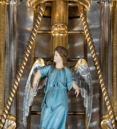 Zdjęcie nr 7: Rokokowa ambona przyścienna uzyskała kształt ożaglowanego okrętu. Składa się z kosza w formie beczkowej łodzi oraz zaplecka w kształcie żagla przechodzącego w baldachim. Kosz został podzielony na dwie strefy. W dolnej przedstawiono stylizowane, srebrzone fale morskie z igrającymi w nich morskimi, złoconymi stworami. Jeden z nich połyka postać Jonasza. Natomiast górną strefę udekorowano złoconymi, rokokowymi kartuszami, skrzyżowanymi dwoma wiosłami okrytymi fragmentem sieci rybackiej na brązowym tle. Z prawej strony do kosza przymocowano złoconą wolutę zdobioną motywem rocalliowym przechodzącym w srebrzony sztandar przymocowany do złotej laski krzyżowej. W zaplecek ambony w kształcie srebrzonego, rozpostartego żagla wstawiono nowy obraz w kształcie stojącego prostokąta, ukazujący błogosławiącego Chrystusa. Zbawiciel został przedstawiony frontalnie w dwóch trzecich postaci z głową i spojrzeniem skierowanym w górę. Prawą ręką błogosławi, lewą zaś przyciska do piersi. Jezus ma pociągłą twarz o wydatnym nosie i ustach, otoczoną brodą i długimi włosami spływającymi na ramiona. Ubrany jest w białą tunikę oraz w przerzucony przez ramię czerwony płaszcz. Jego głowę okala świetlisty nimb na ciemnym tle. Powyżej rozpięty jest baldachim utworzony z masztu podtrzymywanego przez liny i zwisających żagli zakończonych motywem lambrekinowym. Na baldachimie stoi postać uskrzydlonego anioła w luźnej, niebieskiej tunice. Ponad nim na złoconym maszcie umieszczone dwie korony, jedna nad drugą. Na jego szczycie znajduje się gloria z Duchem Świętym w postaci gołębicy na tle srebrzystych obłoków i złotych promieni. Od wschodu do ambony przylegają schody z pełną balustradą artykułowaną romboidalnym płycinami o złoconych krawędziach z polem wypełnionym złoconym motywem rocalliowym. 