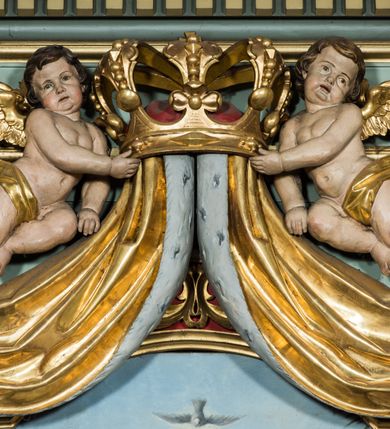 Zdjęcie nr 19: Ołtarz główny uzyskał formę przyściennej, dwukondygnacyjnej, neoklasycystycznej nastawy wzniesionej na rzucie elipsy z bocznymi bramkami. Stipes ołtarzowy uzyskał kształt leżącego prostopadłościanu podtrzymującego drewnianą mensę z portatylem. Jego lico dekorowane jest trzema równoległymi płycinami utworzonymi ze złoconych, profilowanych listew. Na mensie ustawiono prostopadłościenne tabernakulum w formie skrzynki flankowane parą pilastrów podtrzymujących nastawę tronu eucharystycznego. Ujmują go po bokach pary złoconych kolumn z korynckimi kapitelami podtrzymujące belkowanie wygięte na osi półkoliście. Na zwieńczeniu tabernakulum ustawiono leżącego na zamkniętej księdze z siedmioma pieczęciami srebrnego baranka apokaliptycznego na tle srebrzonych promieni. Pomiędzy kolumnami w polu zainstalowano obrotowy bęben z dwiema półkolistymi niszami. Retabulum zostało wsparte na wysokim cokole. Dolną kondygnację artykułują zwielokrotnione pilastry o kanelowanych trzonach i złoconych, kompozytowych głowicach oraz dwie wysunięte do przodu kanelowane kolumny o kapitelach kompozytowych. Podpory podtrzymują szeroki architraw wklęsło-wypukły dekorowany motywami roślinnymi oraz perełkami i ząbkami, wyłamany na przedłużeniu kolumn. W miejscu wyłamań usytuowano siedzących dwóch uskrzydlonych aniołów. Po bokach kolumn na konsolach ustawiono figury św. Piotra i św. Pawła. Boki ołtarza zamykają ażurowe wici roślinne pełniące rolę zredukowanych uszaków. W polu środkowym retabulum umieszczono prostokątne obramienie utworzone z dekoracyjnej ramy zdobionej wicią roślinną oraz podwieszonego u jej góry paludamentum z koroną podtrzymywaną przez dwa aniołki. W środku zainstalowano obraz Matki Boskiej Śnieżnej, a na zasuwie przedstawienie Chrztu Chrystusa w Jordanie. Zwieńczenie nastawy uzyskało kształt leżącego prostokąta flankowanego po bokach parą kanelowanych pilastrów o korynckich głowicach, na tle których ustawiono dwie kolumny podtrzymujących przerwane belkowanie z przerwanym przyczółkiem. Na osi zwieńczenia na postumencie ustawiono rzeźbę św. Michała Archanioła, a na przyczółkach rzeźby dwóch siedzących aniołów. W polu między pilastrami i kolumnami znalazło się płaskorzeźbione przedstawienie Trójcy Przenajświętszej. Dwie flankujące retabulum bramki ozdobiono dwoma aniołkami siedzącymi na ich zwieńczeniu na postumencie. Struktura całości pomalowane jest na zielono, ornamenty i profile wyzłocono, a rzeźby otrzymały naturalistyczną polichromię.