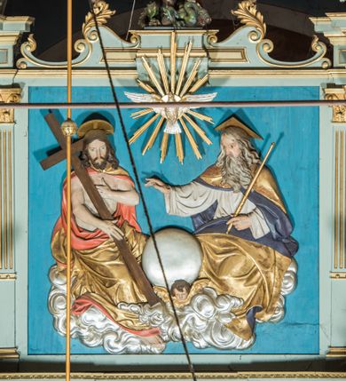 Zdjęcie nr 11: Ołtarz główny uzyskał formę przyściennej, dwukondygnacyjnej, neoklasycystycznej nastawy wzniesionej na rzucie elipsy z bocznymi bramkami. Stipes ołtarzowy uzyskał kształt leżącego prostopadłościanu podtrzymującego drewnianą mensę z portatylem. Jego lico dekorowane jest trzema równoległymi płycinami utworzonymi ze złoconych, profilowanych listew. Na mensie ustawiono prostopadłościenne tabernakulum w formie skrzynki flankowane parą pilastrów podtrzymujących nastawę tronu eucharystycznego. Ujmują go po bokach pary złoconych kolumn z korynckimi kapitelami podtrzymujące belkowanie wygięte na osi półkoliście. Na zwieńczeniu tabernakulum ustawiono leżącego na zamkniętej księdze z siedmioma pieczęciami srebrnego baranka apokaliptycznego na tle srebrzonych promieni. Pomiędzy kolumnami w polu zainstalowano obrotowy bęben z dwiema półkolistymi niszami. Retabulum zostało wsparte na wysokim cokole. Dolną kondygnację artykułują zwielokrotnione pilastry o kanelowanych trzonach i złoconych, kompozytowych głowicach oraz dwie wysunięte do przodu kanelowane kolumny o kapitelach kompozytowych. Podpory podtrzymują szeroki architraw wklęsło-wypukły dekorowany motywami roślinnymi oraz perełkami i ząbkami, wyłamany na przedłużeniu kolumn. W miejscu wyłamań usytuowano siedzących dwóch uskrzydlonych aniołów. Po bokach kolumn na konsolach ustawiono figury św. Piotra i św. Pawła. Boki ołtarza zamykają ażurowe wici roślinne pełniące rolę zredukowanych uszaków. W polu środkowym retabulum umieszczono prostokątne obramienie utworzone z dekoracyjnej ramy zdobionej wicią roślinną oraz podwieszonego u jej góry paludamentum z koroną podtrzymywaną przez dwa aniołki. W środku zainstalowano obraz Matki Boskiej Śnieżnej, a na zasuwie przedstawienie Chrztu Chrystusa w Jordanie. Zwieńczenie nastawy uzyskało kształt leżącego prostokąta flankowanego po bokach parą kanelowanych pilastrów o korynckich głowicach, na tle których ustawiono dwie kolumny podtrzymujących przerwane belkowanie z przerwanym przyczółkiem. Na osi zwieńczenia na postumencie ustawiono rzeźbę św. Michała Archanioła, a na przyczółkach rzeźby dwóch siedzących aniołów. W polu między pilastrami i kolumnami znalazło się płaskorzeźbione przedstawienie Trójcy Przenajświętszej. Dwie flankujące retabulum bramki ozdobiono dwoma aniołkami siedzącymi na ich zwieńczeniu na postumencie. Struktura całości pomalowane jest na zielono, ornamenty i profile wyzłocono, a rzeźby otrzymały naturalistyczną polichromię.