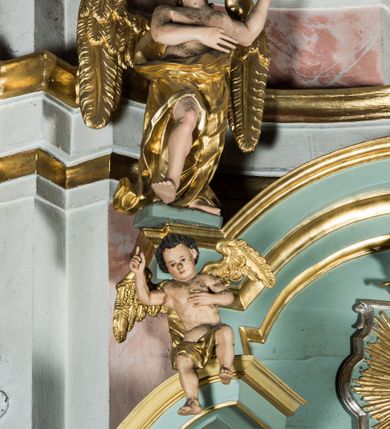 Zdjęcie nr 7: Przyścienny, wczesnoklasycystyczny ołtarz uzyskał formę architektonicznej, jednokondygnacyjnej nastawy ze zwieńczeniem. Sarkofagowy stipes ołtarzowy podtrzymuje drewnianą mensy, na której ustawiono prostopadłościenne tabernakulum w formie skrzynki. Złocone drzwiczki ozdobiono płaskorzeźbionym przedstawieniem kielicha ustawionego na obłokach z hostią otoczoną promieniami. Tabernakulum flankują dwie wypukło wklęsłe płyciny zawierające obraz ze scena pokłonu Trzech Króli oraz Zmartwychwstanie Chrystusa. Powyżej wzniesiono retabulum artykułowane po bokach kanelowanymi pilastrami z kompozytowymi głowicami, podtrzymującymi wyłamane po zewnętrznych belkowanie, dodatkowo wsparte na ustawionych w narożach konsolach. Konsole ozdobiono ornament z motywem  stylizowanej muszli. Na belkowaniu wsparto przerwany przyczółek, na bokach którego siedzą dwa uskrzydlone anioły. Zwieńczenie utworzono z lezącego prostokąta o wklęsłych bokach zwieńczonego profilowanym gzymsem ujętym w nadwieszony łuk odcinkowy. Na jego szczycie po bokach ustawiono dwa stojące uskrzydlone anioły. W polu zwieńczenia znalazł się płaskorzeźbiony chrystogram "IHS" w promienistej glorii. Powyżej umieszczono parę uskrzydlonych główek anielskich. Z kolei w polu kondygnacji między pilastrami usytuowano półokrągłą niszę z figurą Najświętszego Serca Pana Jezusa. Na tle pilastrów dostawione zostały posągi św. Barbary i św. Marii Magdaleny. Struktura została pomalowana w kolorze jasnego seledynu, ornamenty i profile wyzłocono, a rzeźby otrzymały naturalistyczną polichromię.
