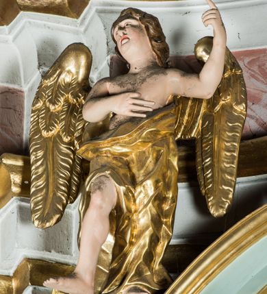 Zdjęcie nr 9: Przyścienny, wczesnoklasycystyczny ołtarz uzyskał formę architektonicznej, jednokondygnacyjnej nastawy ze zwieńczeniem. Sarkofagowy stipes ołtarzowy podtrzymuje drewnianą mensy, na której ustawiono prostopadłościenne tabernakulum w formie skrzynki. Złocone drzwiczki ozdobiono płaskorzeźbionym przedstawieniem kielicha ustawionego na obłokach z hostią otoczoną promieniami. Tabernakulum flankują dwie wypukło wklęsłe płyciny zawierające obraz ze scena pokłonu Trzech Króli oraz Zmartwychwstanie Chrystusa. Powyżej wzniesiono retabulum artykułowane po bokach kanelowanymi pilastrami z kompozytowymi głowicami, podtrzymującymi wyłamane po zewnętrznych belkowanie, dodatkowo wsparte na ustawionych w narożach konsolach. Konsole ozdobiono ornament z motywem  stylizowanej muszli. Na belkowaniu wsparto przerwany przyczółek, na bokach którego siedzą dwa uskrzydlone anioły. Zwieńczenie utworzono z lezącego prostokąta o wklęsłych bokach zwieńczonego profilowanym gzymsem ujętym w nadwieszony łuk odcinkowy. Na jego szczycie po bokach ustawiono dwa stojące uskrzydlone anioły. W polu zwieńczenia znalazł się płaskorzeźbiony chrystogram "IHS" w promienistej glorii. Powyżej umieszczono parę uskrzydlonych główek anielskich. Z kolei w polu kondygnacji między pilastrami usytuowano półokrągłą niszę z figurą Najświętszego Serca Pana Jezusa. Na tle pilastrów dostawione zostały posągi św. Barbary i św. Marii Magdaleny. Struktura została pomalowana w kolorze jasnego seledynu, ornamenty i profile wyzłocono, a rzeźby otrzymały naturalistyczną polichromię.