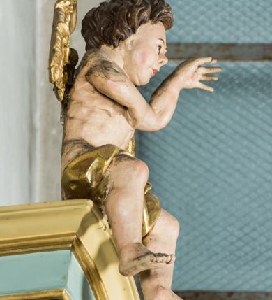 Zdjęcie nr 10: Przyścienny, wczesnoklasycystyczny ołtarz uzyskał formę architektonicznej, jednokondygnacyjnej nastawy ze zwieńczeniem. Sarkofagowy stipes ołtarzowy podtrzymuje drewnianą mensy, na której ustawiono prostopadłościenne tabernakulum w formie skrzynki. Złocone drzwiczki ozdobiono płaskorzeźbionym przedstawieniem kielicha ustawionego na obłokach z hostią otoczoną promieniami. Tabernakulum flankują dwie wypukło wklęsłe płyciny zawierające obraz ze scena pokłonu Trzech Króli oraz Zmartwychwstanie Chrystusa. Powyżej wzniesiono retabulum artykułowane po bokach kanelowanymi pilastrami z kompozytowymi głowicami, podtrzymującymi wyłamane po zewnętrznych belkowanie, dodatkowo wsparte na ustawionych w narożach konsolach. Konsole ozdobiono ornament z motywem  stylizowanej muszli. Na belkowaniu wsparto przerwany przyczółek, na bokach którego siedzą dwa uskrzydlone anioły. Zwieńczenie utworzono z lezącego prostokąta o wklęsłych bokach zwieńczonego profilowanym gzymsem ujętym w nadwieszony łuk odcinkowy. Na jego szczycie po bokach ustawiono dwa stojące uskrzydlone anioły. W polu zwieńczenia znalazł się płaskorzeźbiony chrystogram "IHS" w promienistej glorii. Powyżej umieszczono parę uskrzydlonych główek anielskich. Z kolei w polu kondygnacji między pilastrami usytuowano półokrągłą niszę z figurą Najświętszego Serca Pana Jezusa. Na tle pilastrów dostawione zostały posągi św. Barbary i św. Marii Magdaleny. Struktura została pomalowana w kolorze jasnego seledynu, ornamenty i profile wyzłocono, a rzeźby otrzymały naturalistyczną polichromię.