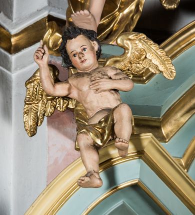 Zdjęcie nr 13: Przyścienny, wczesnoklasycystyczny ołtarz uzyskał formę architektonicznej, jednokondygnacyjnej nastawy ze zwieńczeniem. Sarkofagowy stipes ołtarzowy podtrzymuje drewnianą mensy, na której ustawiono prostopadłościenne tabernakulum w formie skrzynki. Złocone drzwiczki ozdobiono płaskorzeźbionym przedstawieniem kielicha ustawionego na obłokach z hostią otoczoną promieniami. Tabernakulum flankują dwie wypukło wklęsłe płyciny zawierające obraz ze scena pokłonu Trzech Króli oraz Zmartwychwstanie Chrystusa. Powyżej wzniesiono retabulum artykułowane po bokach kanelowanymi pilastrami z kompozytowymi głowicami, podtrzymującymi wyłamane po zewnętrznych belkowanie, dodatkowo wsparte na ustawionych w narożach konsolach. Konsole ozdobiono ornament z motywem  stylizowanej muszli. Na belkowaniu wsparto przerwany przyczółek, na bokach którego siedzą dwa uskrzydlone anioły. Zwieńczenie utworzono z lezącego prostokąta o wklęsłych bokach zwieńczonego profilowanym gzymsem ujętym w nadwieszony łuk odcinkowy. Na jego szczycie po bokach ustawiono dwa stojące uskrzydlone anioły. W polu zwieńczenia znalazł się płaskorzeźbiony chrystogram "IHS" w promienistej glorii. Powyżej umieszczono parę uskrzydlonych główek anielskich. Z kolei w polu kondygnacji między pilastrami usytuowano półokrągłą niszę z figurą Najświętszego Serca Pana Jezusa. Na tle pilastrów dostawione zostały posągi św. Barbary i św. Marii Magdaleny. Struktura została pomalowana w kolorze jasnego seledynu, ornamenty i profile wyzłocono, a rzeźby otrzymały naturalistyczną polichromię.