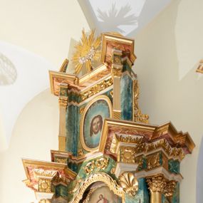 Zdjęcie nr 1: Ołtarz przyścienny, architektoniczny, jednoosiowy, jednokondygnacyjny ze zwieńczeniem. Mensa prostopadłościenna, w antepedium prostokątna płycina, w której umieszczony jest kurdyban, wytłaczany, barwiony i złocony z dekoracją ornamentalną składającą się z karbowanych taśm i motywów zwierzęcych oraz roślinnych. Retabulum ustawione na wysokim, dwustrefowym cokole, zamkniętym wyłamanym i profilowanym gzymsem. Predella ołtarza dekorowana owalnym, poziomym kartuszem ujętym ażurowymi, splecionymi liśćmi bujnego akantu i karbowanej wstęgi. Nastawa ołtarzowa flankowana parą filarów i kolumn ustawionych na tle pilastrów. Trzony kolumn do jednej trzeciej wysokości spiralnie skręcone, powyżej gładkie z grawerowaną wicią winorośli; trzony pilastrów do jednej trzeciej wysokości kanelowane, powyżej oplecione ukośnie wieńcem wawrzynu; kapitele podpór korynckie. Podpory wspierają wyłamane belkowanie, przerwane nad częścią środkową, zamknięte wydatnym, profilowanym gzymsem. W polu środkowym nastawy wnęka ze zdwojoną ramą w kształcie stojącego prostokąta, zamkniętego łukiem wklęsło-wypukłym z uskokami z obrazami „Przemienienie Pańskie” oraz „Ostatnia Wieczerza” na zasuwie. Na osi filarów w partii belkowania ustawione są pod kątem imposty, podtrzymywane przez płaskie, stylizowane muszle. Na tle filarów znajdują się figury: po lewej stronie Mojżesza, a po prawej Eliasza. Zwieńczenie w kształcie stojącego prostokąta, ujęte parą ukośnie dostawionych filarów, wspierających wyłamane belkowanie. Filary do jednej trzeciej wysokości zdobione ukośnym żłobkowaniem, powyżej kanelowane, kapitele korynckie. W polu środkowym owalny wizerunek twarzy Chrystusa. Na szczycie zwieńczenia oko Opatrzności wpisane w trójkąt, ujęte od dołu srebrzonymi obłokami i ukazane na tle promienistej glorii. Dekoracja ornamentalna: przednie ścianki cokołów dekorowane rozetami, po bokach cokołów owalne kartusze ujęte wydłużonymi liśćmi przeplecionymi karbowaną wstęgą; fryz dekorowany rozetami kwiatowymi; poniżej gzymsu ornament z liści akantu; po bokach zwieńczenia uszaki formowane z ażurowej wici roślinnej. Całość struktury ołtarza pokryta marmoryzacją zielono-niebieską; w dolnej części cokołu i w partiach belkowania w kolorze czerwono-różowym. Detale oraz profilowania pozłacane i posrebrzane. 